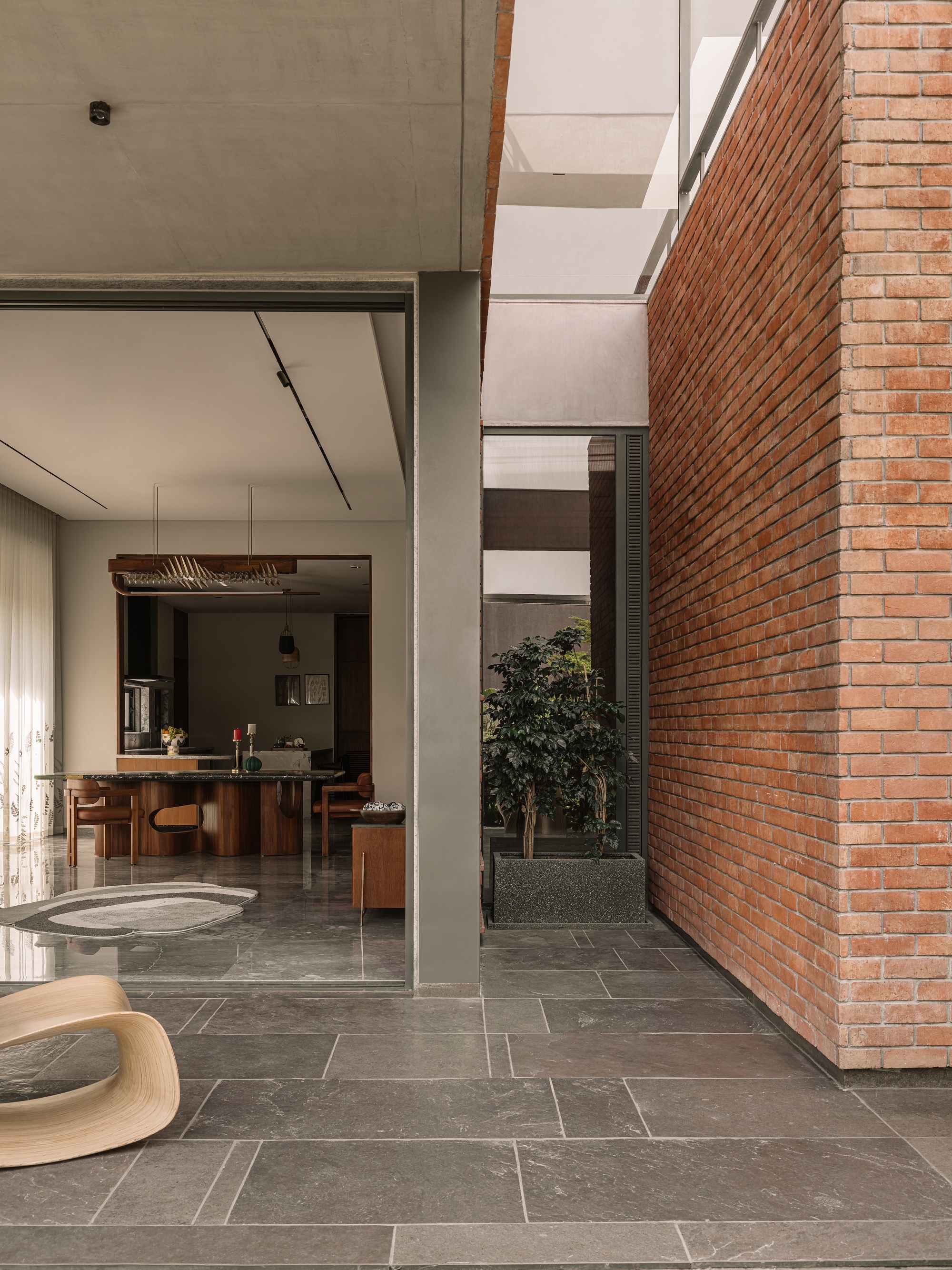 Exposed red brick wall beside a slate-paved terrace and sliding glass opening onto a dining area in soft daylight