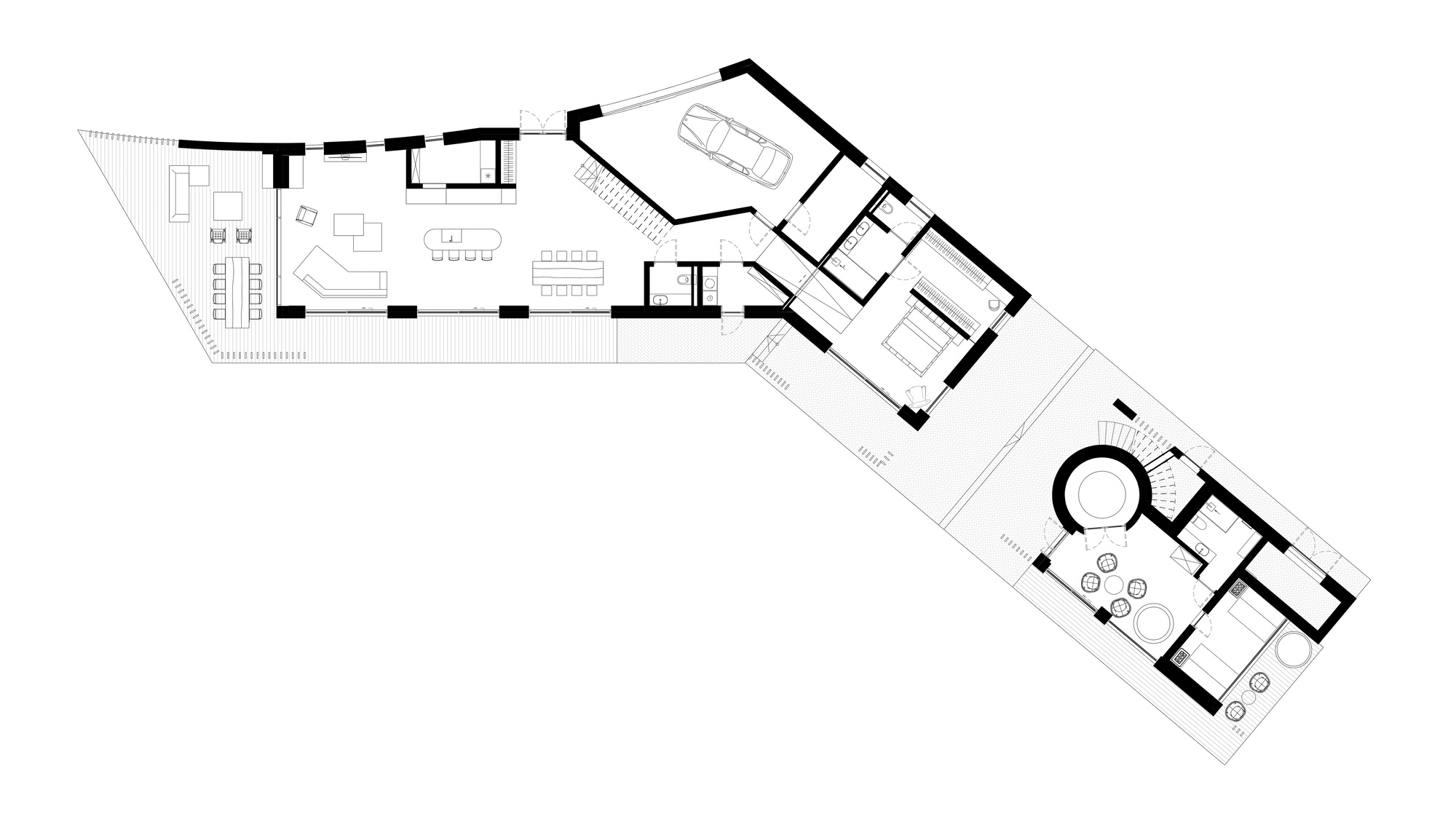 Floor plan drawing showing two angled wings joined at a bend, with living spaces, garage, bedrooms and a round stair tower