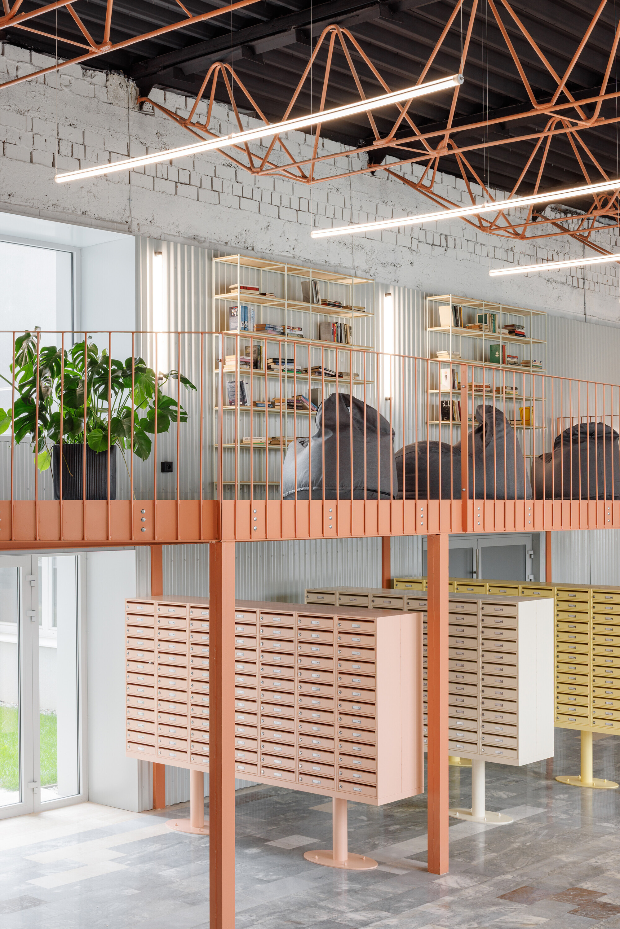 Mezzanine with shelves and bean bags above pastel mailbox units, under coral truss lamps and linear lights
