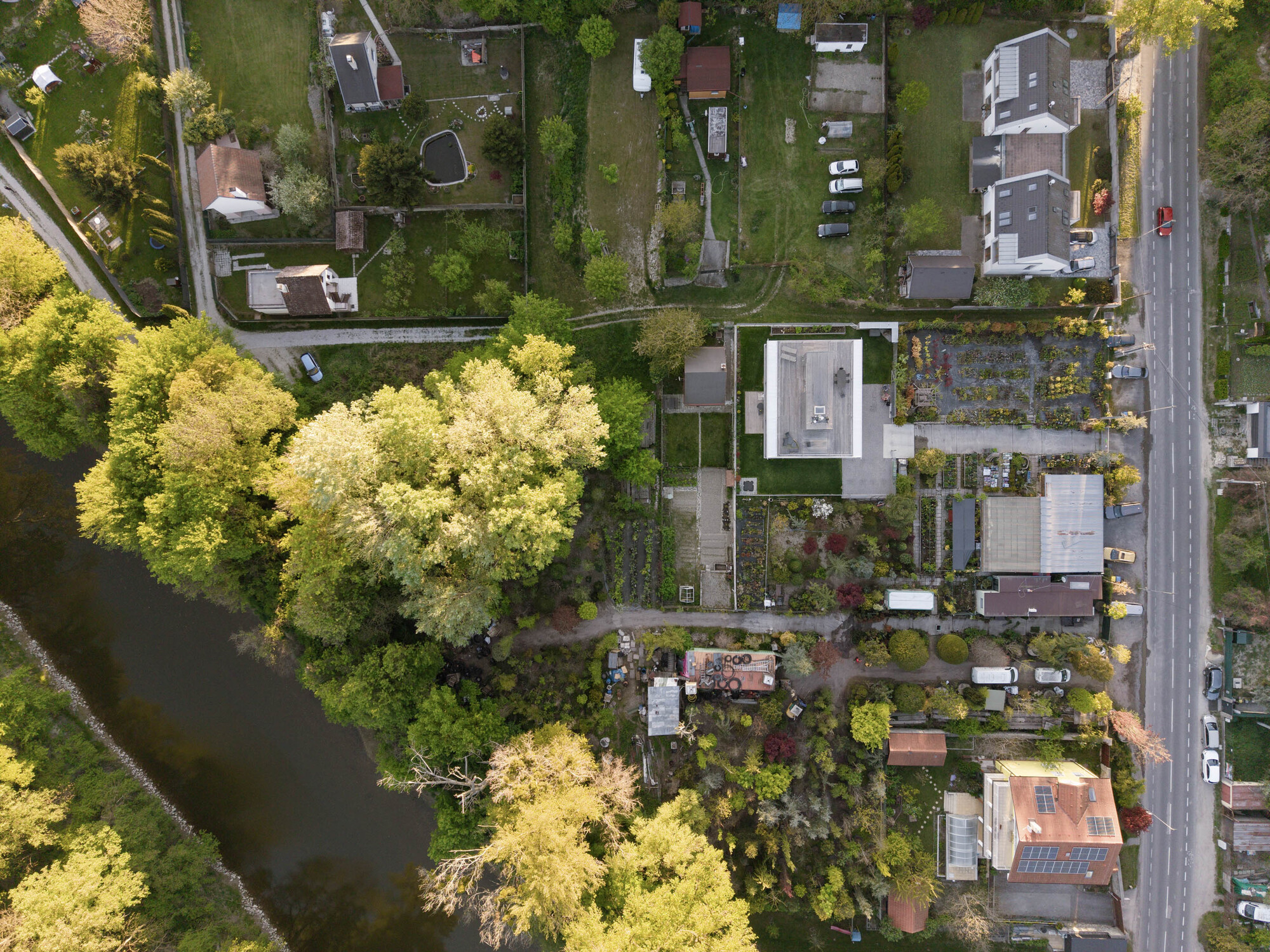 Aerial view of the house with a flat roof among neighbouring gardens, a river and a road lined with parked cars