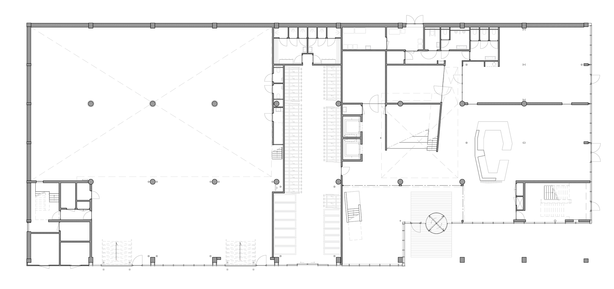 Ground floor plan drawing showing a large column grid on the left, central stairs and service cores, and smaller rooms on the right