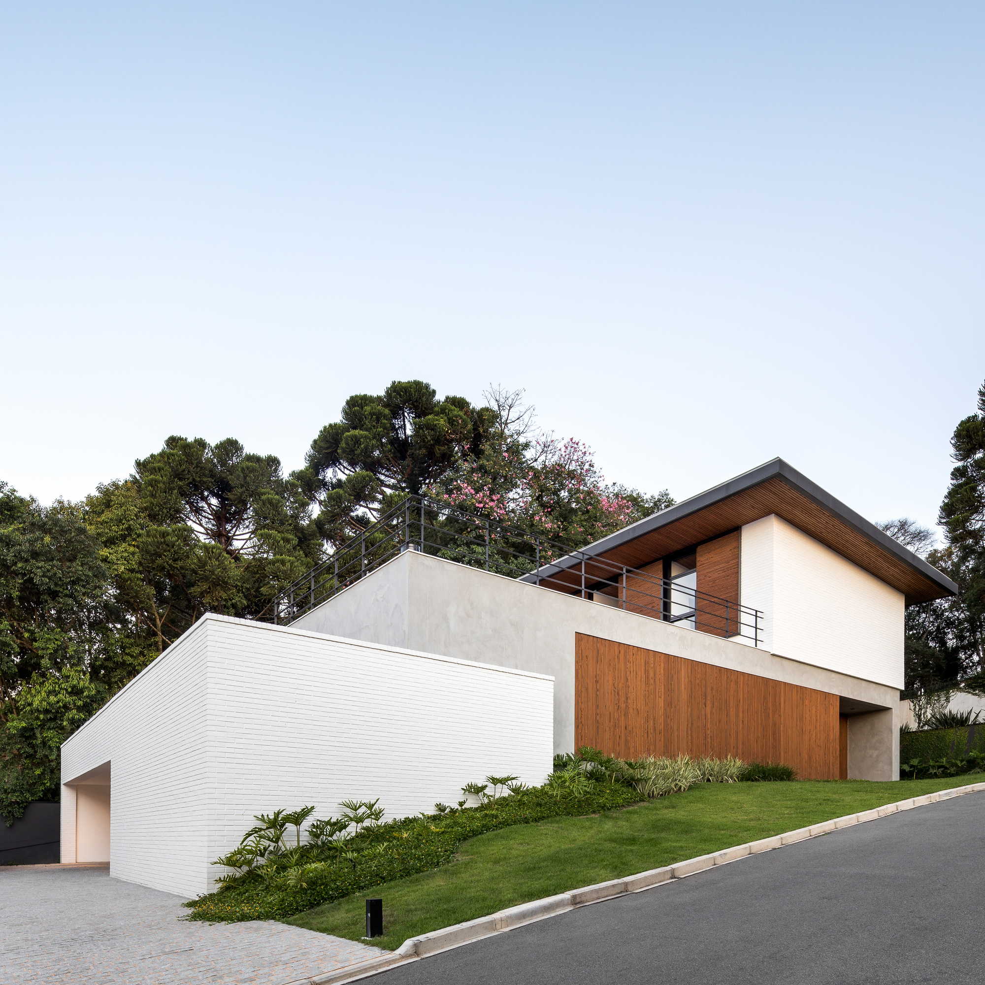 Corner view of the white brick garage wall and concrete base stepping up a grassy slope at dusk