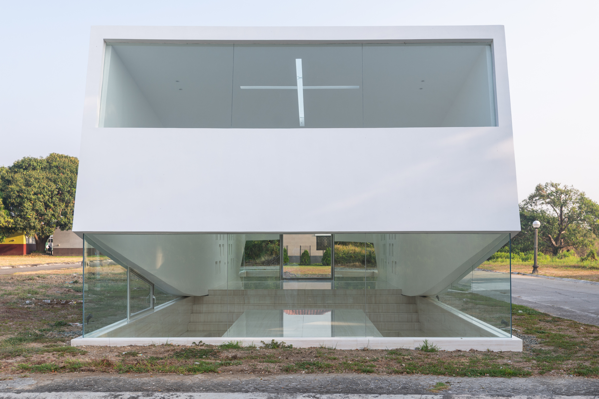 Front elevation of the white box floating above a glass base, with a cross-shaped skylight slit visible inside