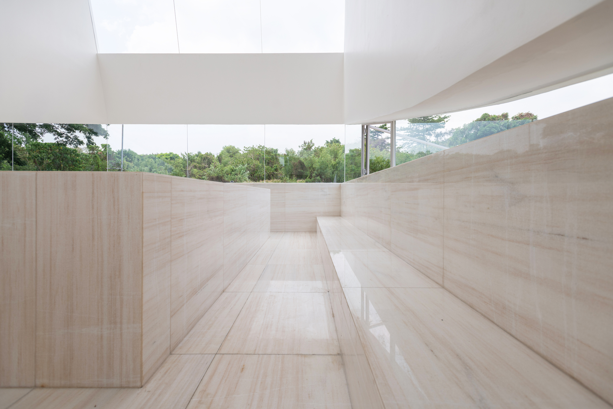 Narrow stone-clad passage with a built-in bench and a glazed band framing the treetops outside
