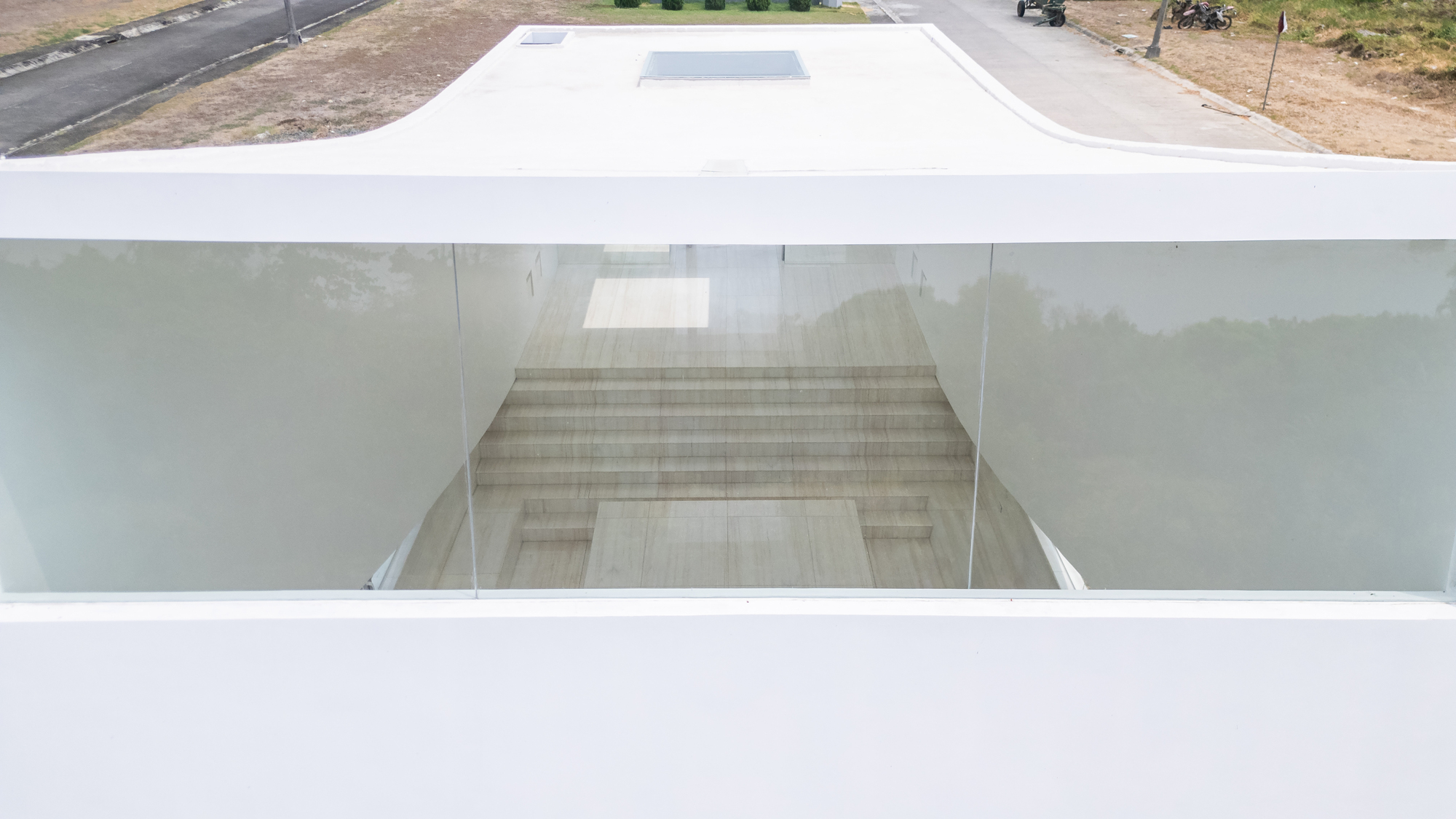 Drone view looking through the glazed front to travertine steps and an altar block, framed by the white roof edge