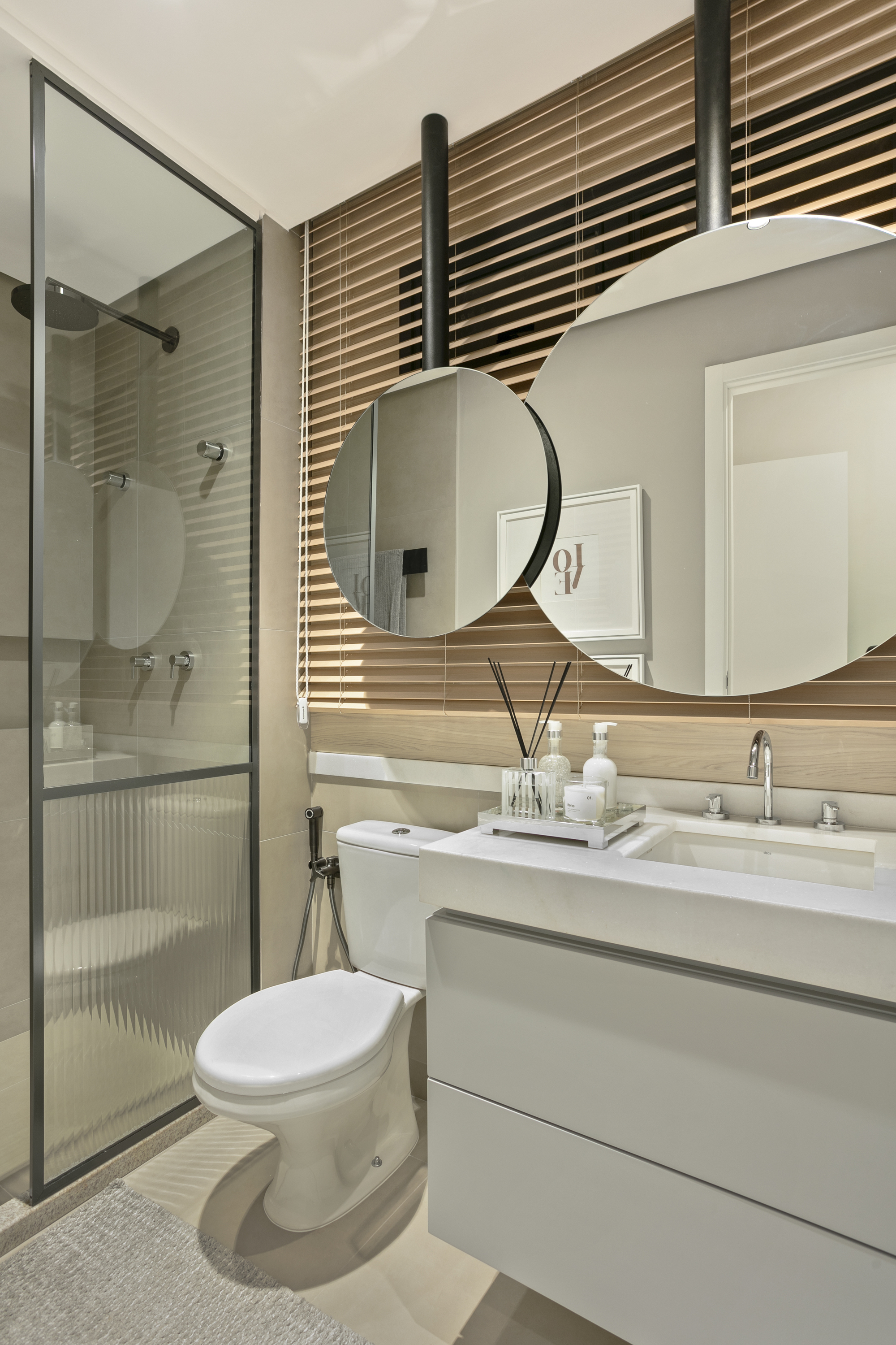 Bathroom with two round mirrors hung from ceiling rods, a fluted glass shower screen and timber blinds behind a floating vanity