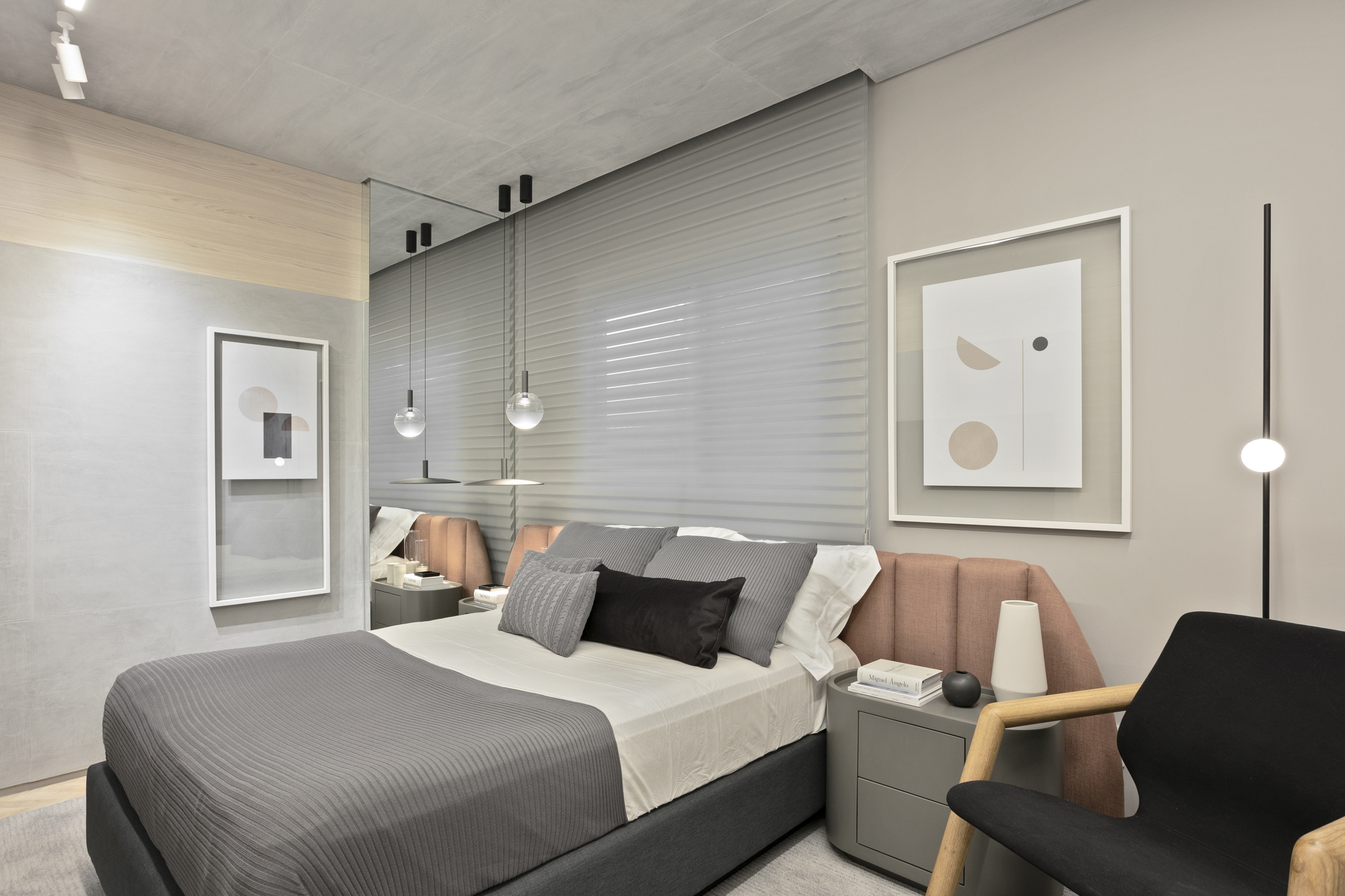 Bedroom with a pink upholstered headboard, mirrored side panel and glass pendant lights, with a black armchair in the corner