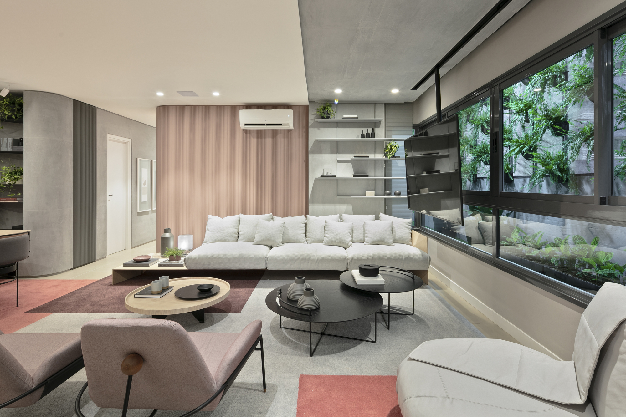 Living room with a low white sofa against a blush wood panel wall, beside a window of hanging ferns