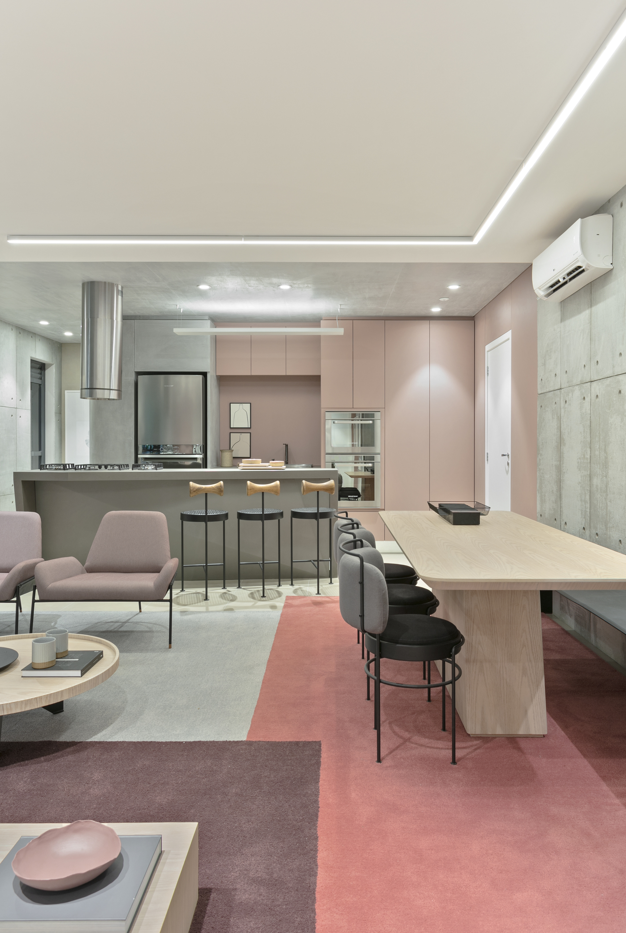 Open kitchen and dining space with blush cabinetry, bar stools and a coral and mauve rug in soft evening light