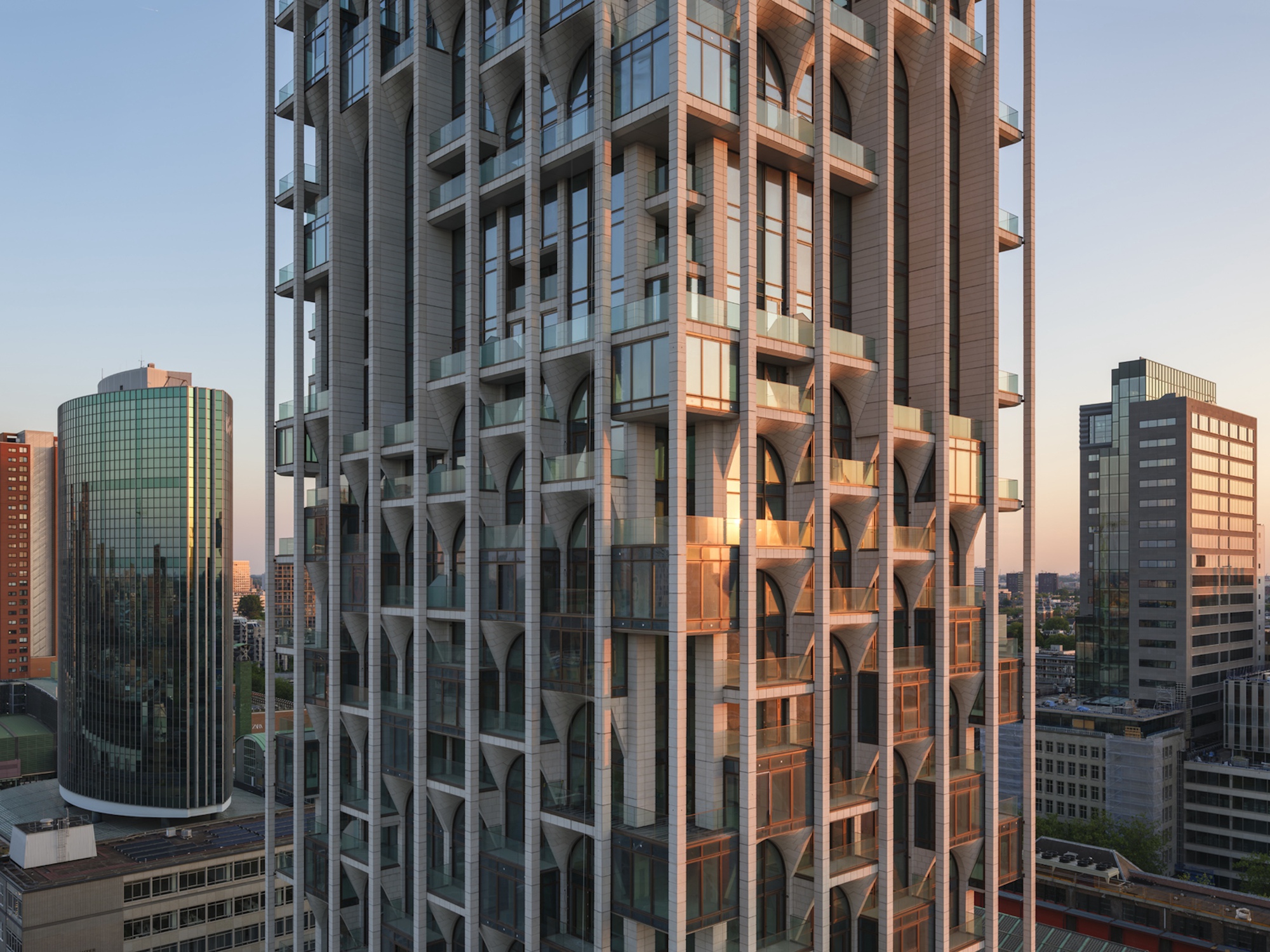 Close view of the tower facade with tapered brackets, arched windows and balconies, glowing in warm sunset light
