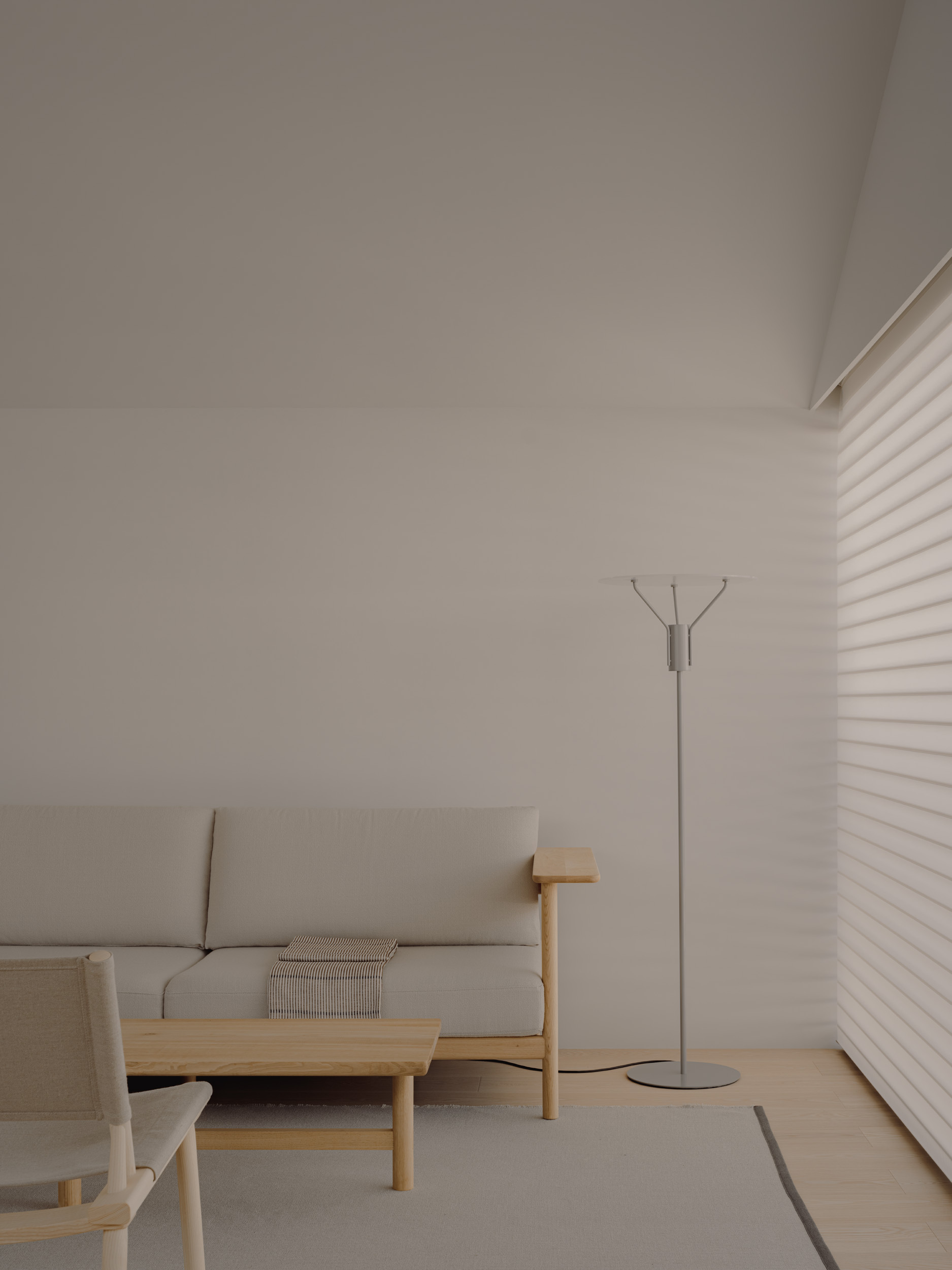 Living corner with pale sofa, low timber table and slim floor lamp beside a window with sheer horizontal blinds