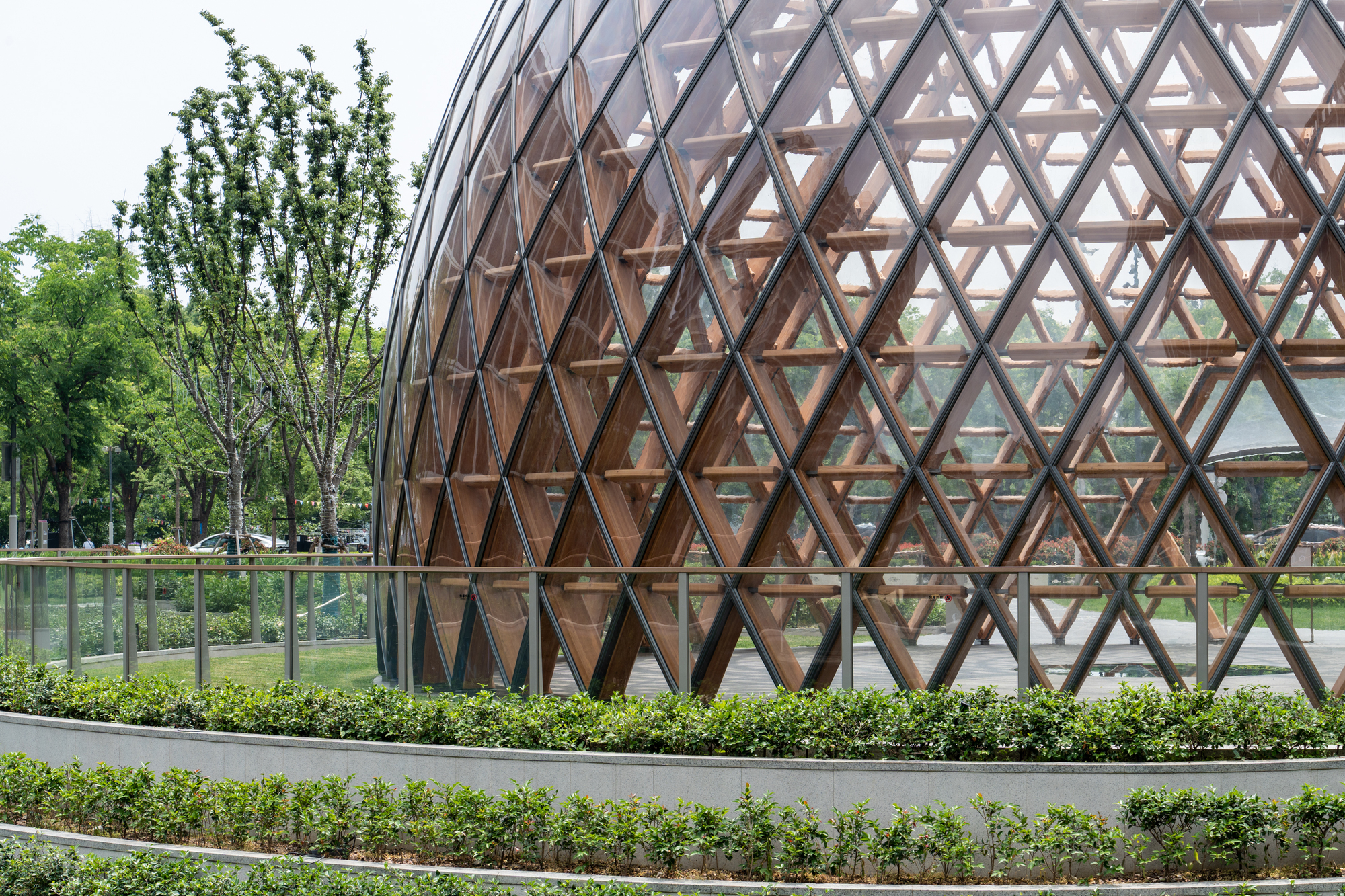 Close-up of the diamond timber lattice and glazing on the dome, behind a glass balustrade and clipped hedge rows