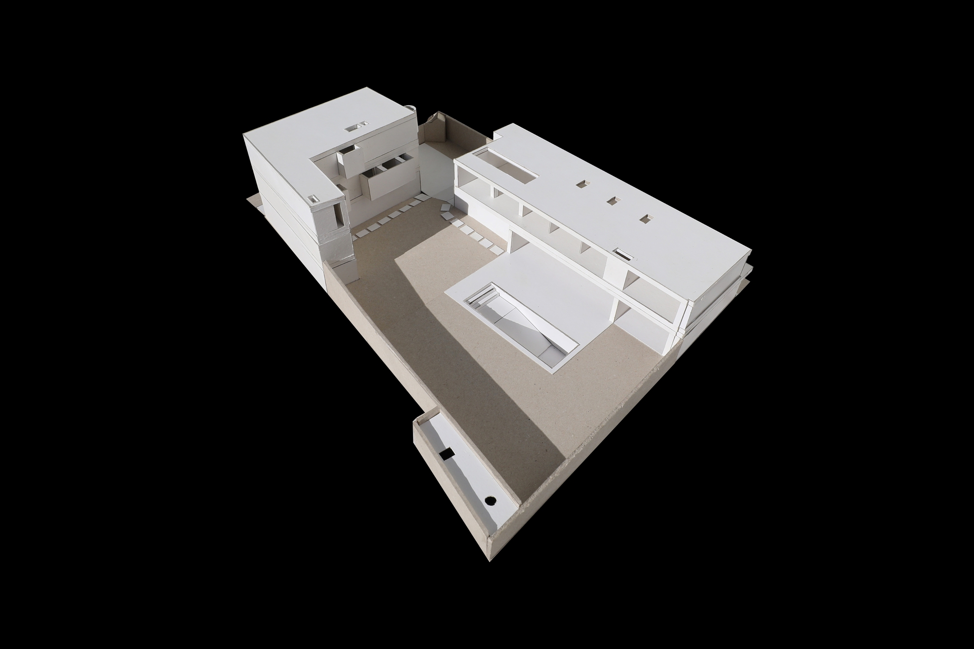 High angle view of the white site model with a rooftop skylight and a rectangular pool set in a paved courtyard