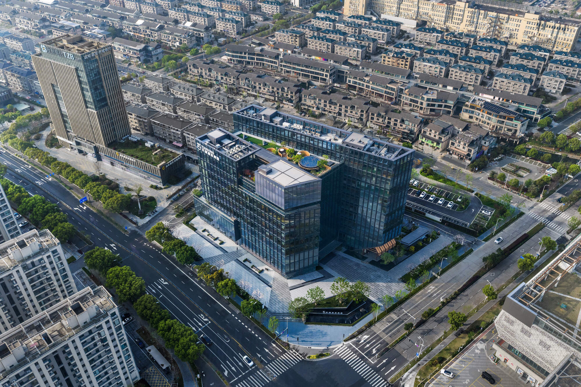 Aerial view of the stepped glass office blocks with rooftop gardens, ringed by roads and low-rise housing in daylight