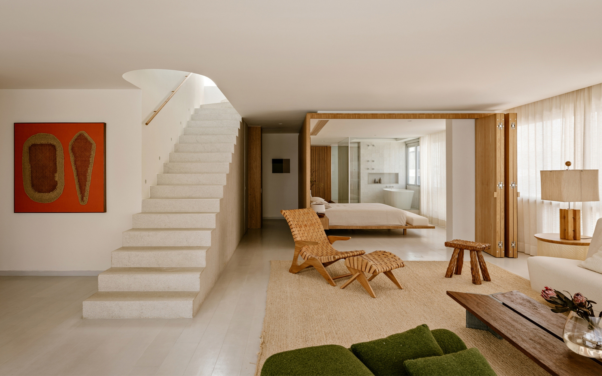 Open living space with a floating limestone stair, orange wall artwork and a folding timber screen opening onto the bedroom and bathtub