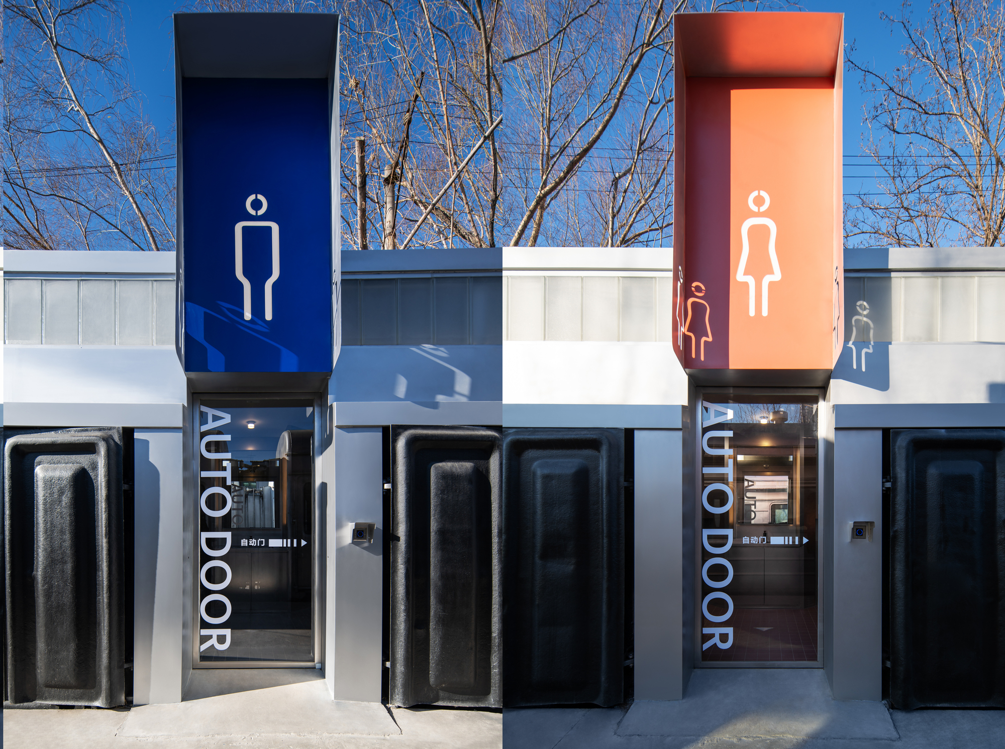 Paired restroom entrances with blue and orange signage boxes, glass doors lettered AUTO DOOR and black wagon panels, bare branches above