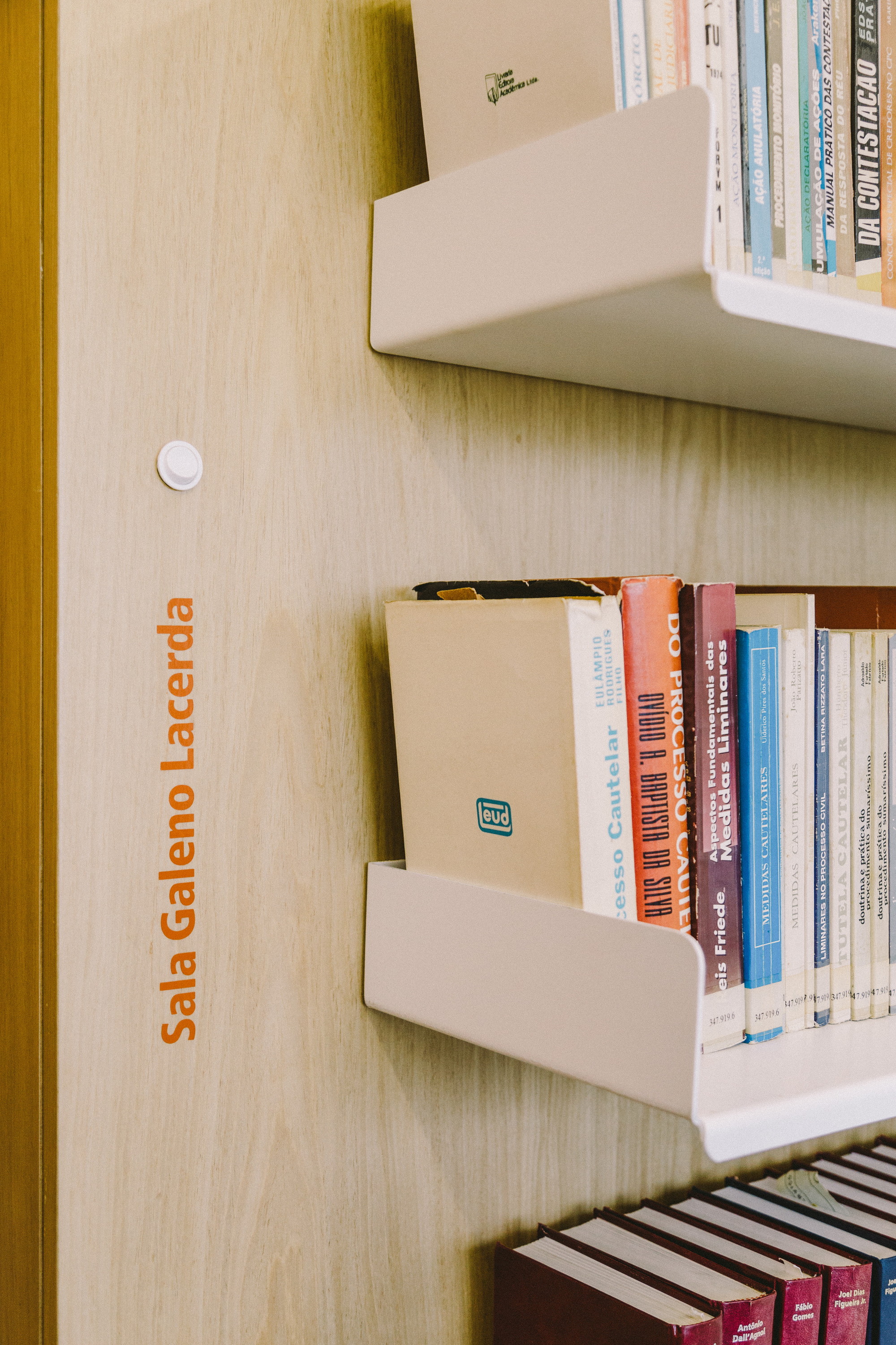 Oak panel with orange room lettering beside white folded-metal shelves holding worn law books in soft daylight