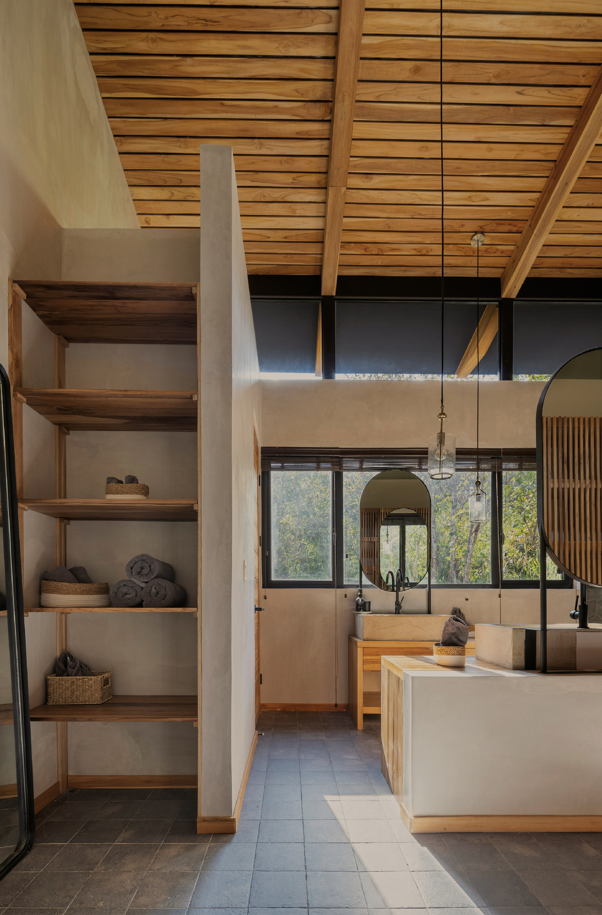 Bathroom with open timber shelving of rolled towels, slate floor and a stone vanity under a slatted ceiling