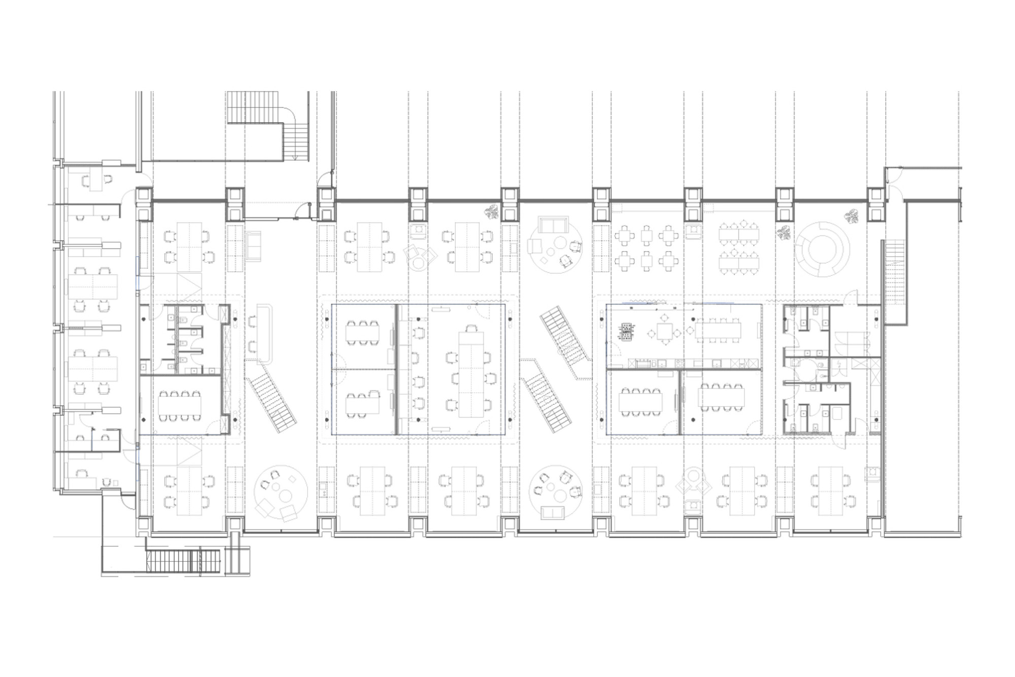 Floor plan drawing of a long office level with desk clusters, meeting rooms, restrooms and two stairs between structural columns