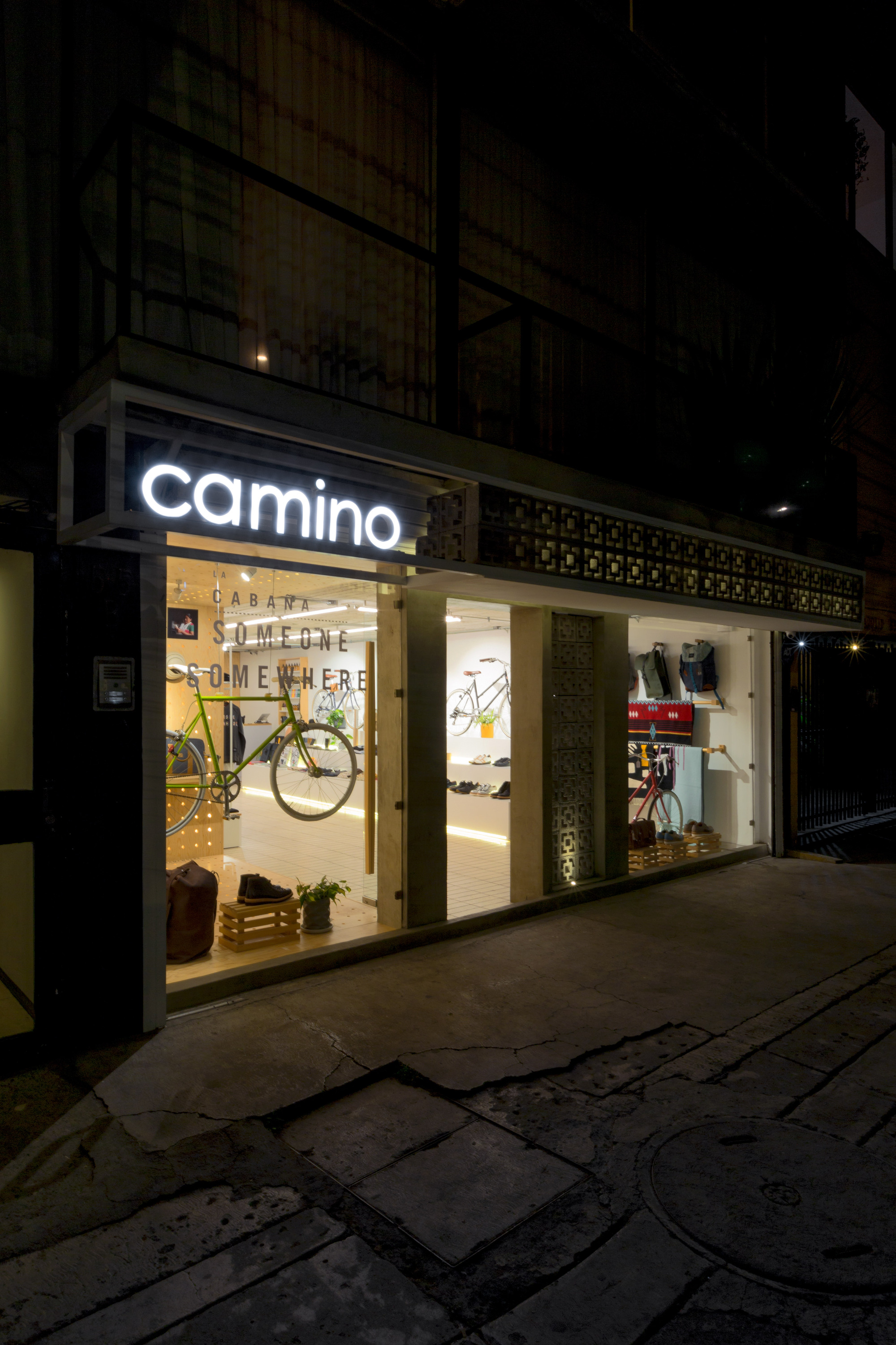 Night view of the glazed storefront with an illuminated sign and a perforated block screen between display windows