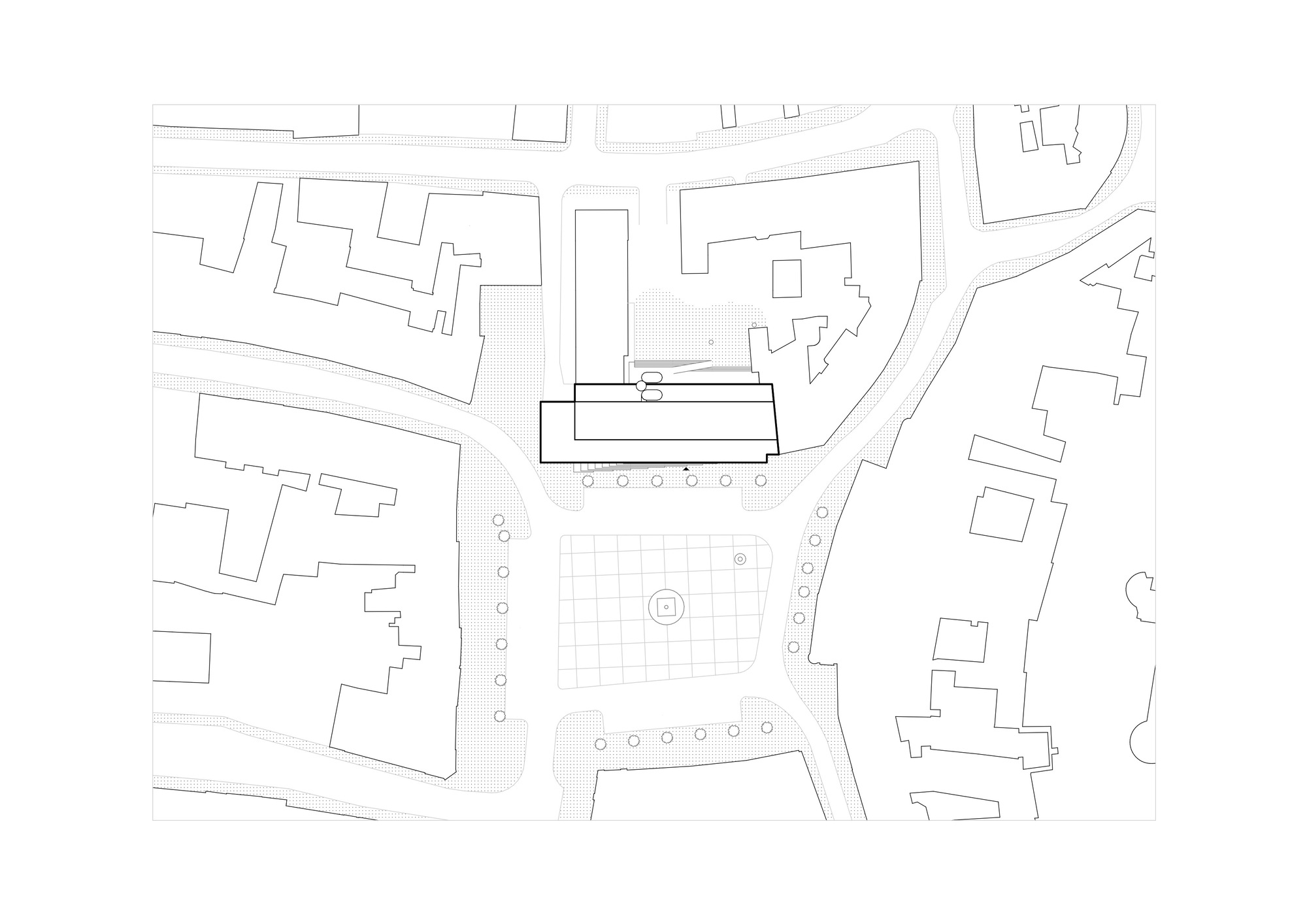 Site plan drawing showing the building footprint outlined in bold among surrounding street blocks and a paved square with tree rows