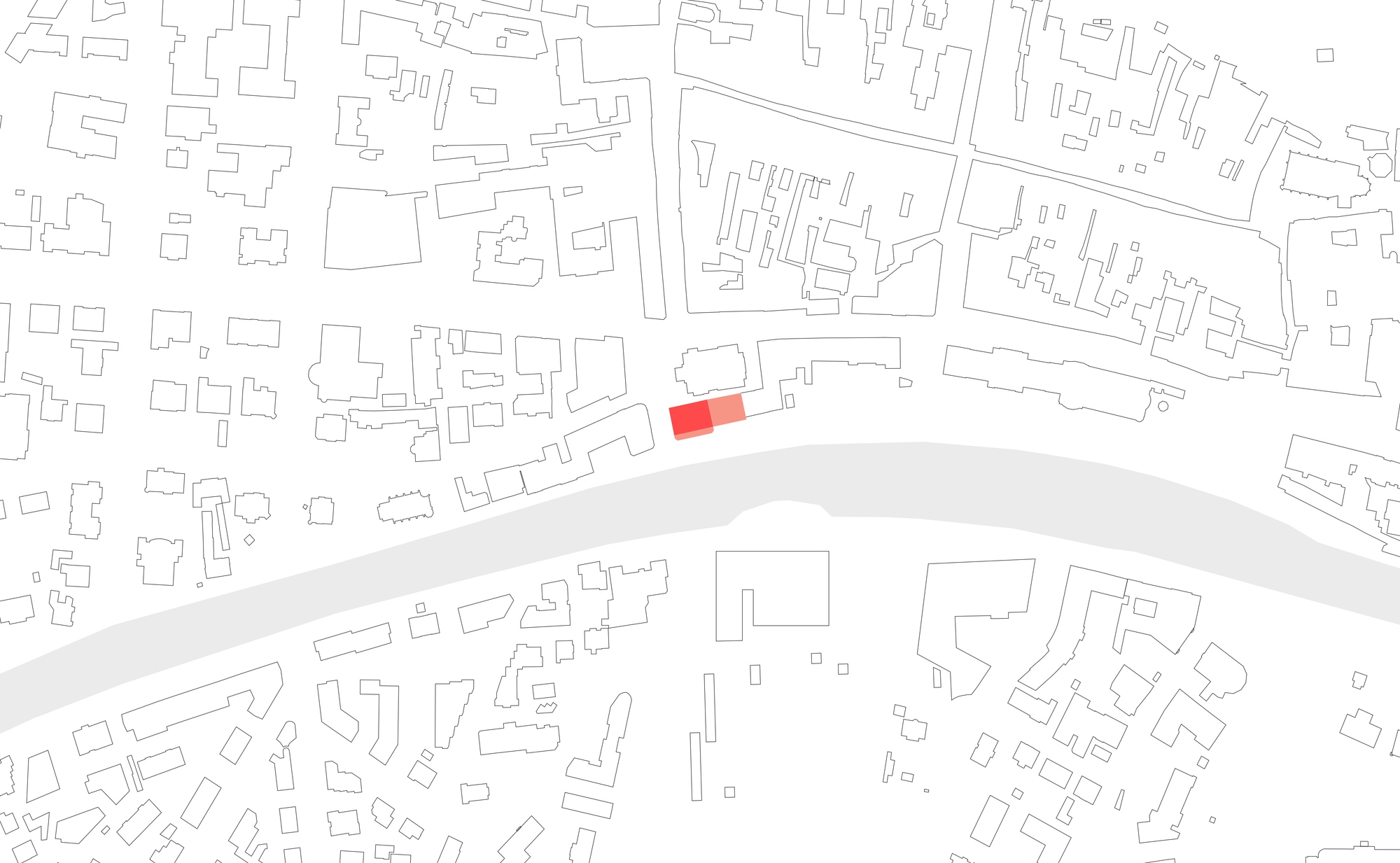 Site plan drawing with a red building footprint on a street running along a wide grey river, surrounded by outlined blocks