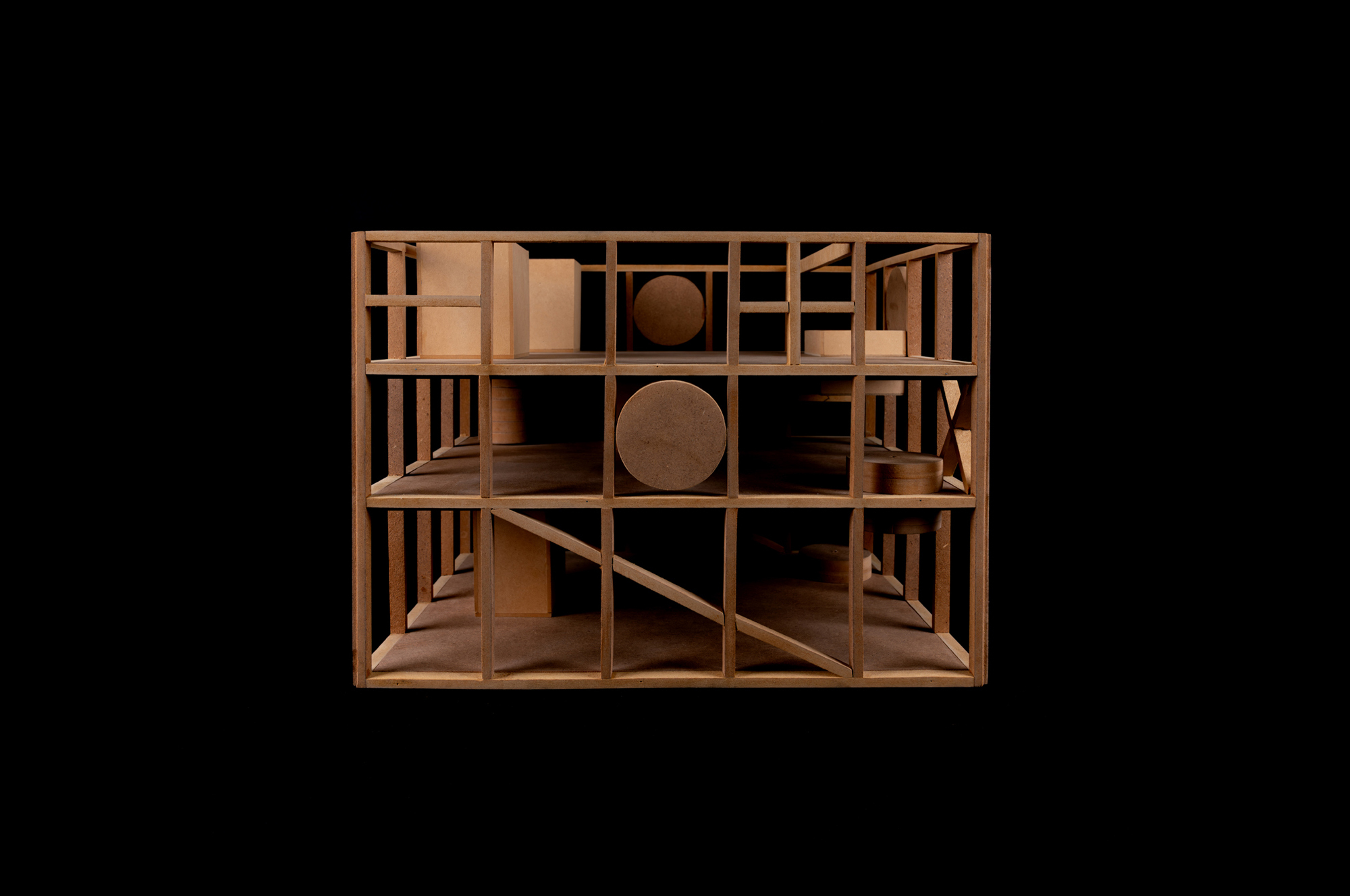 Wooden study model of the timber-like frame against a black background, with cylinders and blocks inside and a diagonal brace on the lower level