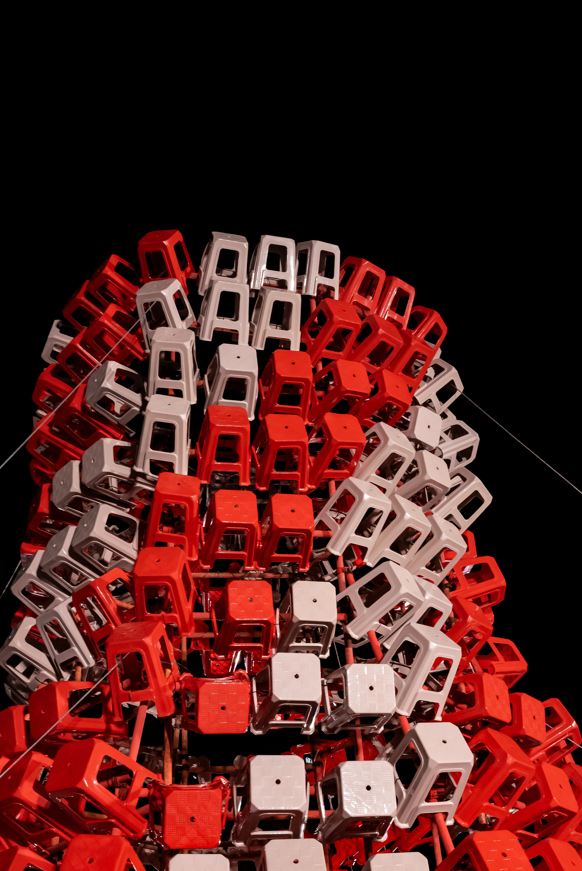 Low angle of the stool tower at night, red and white stools forming diagonal bands against black sky