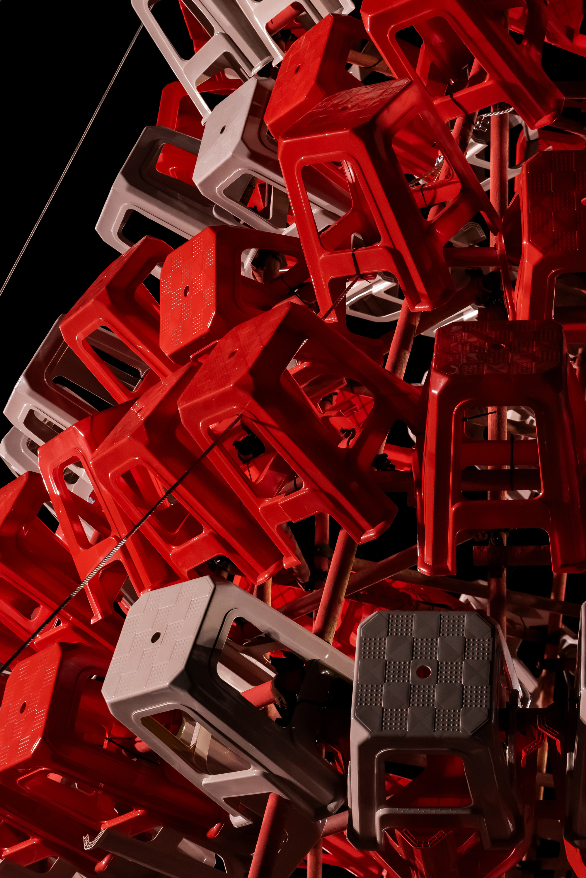 Close-up of stools mounted at varied angles on thin red steel rods against a dark night sky