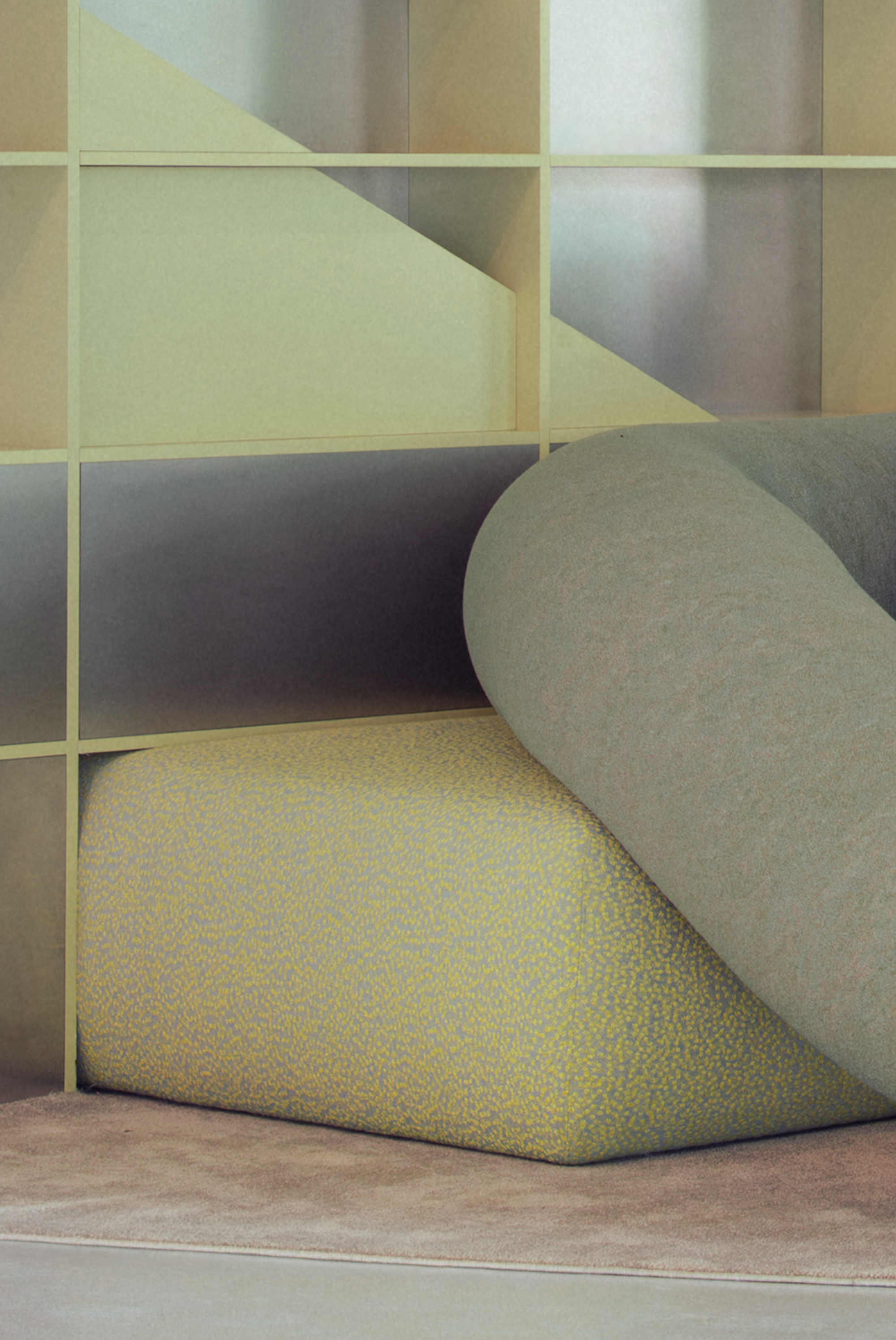 Close-up of a speckled yellow upholstered block and a grey rolled cushion resting against a grid shelf with frosted panels