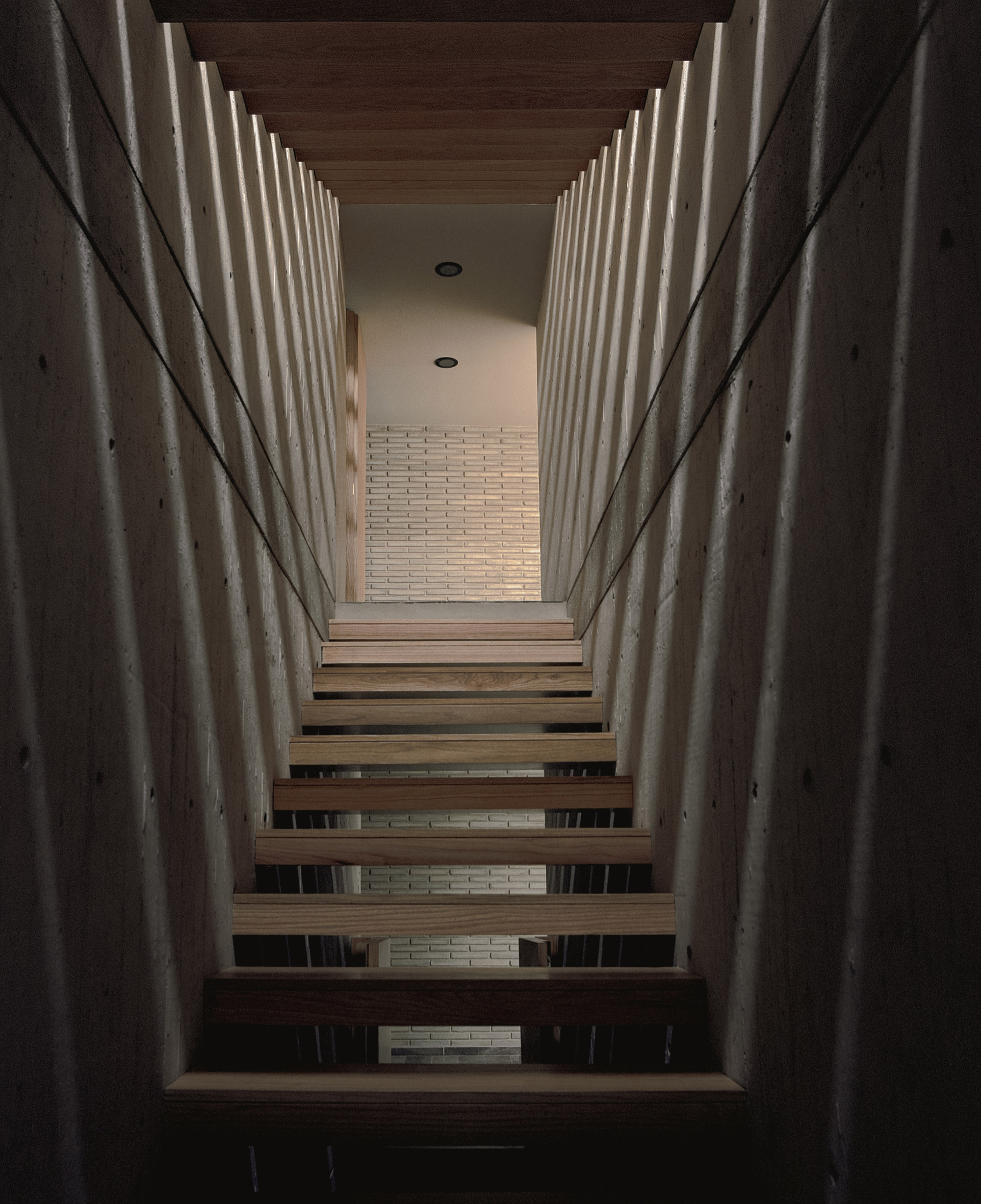 Narrow stair of floating timber treads between board-marked concrete walls, with slatted light falling across the surfaces