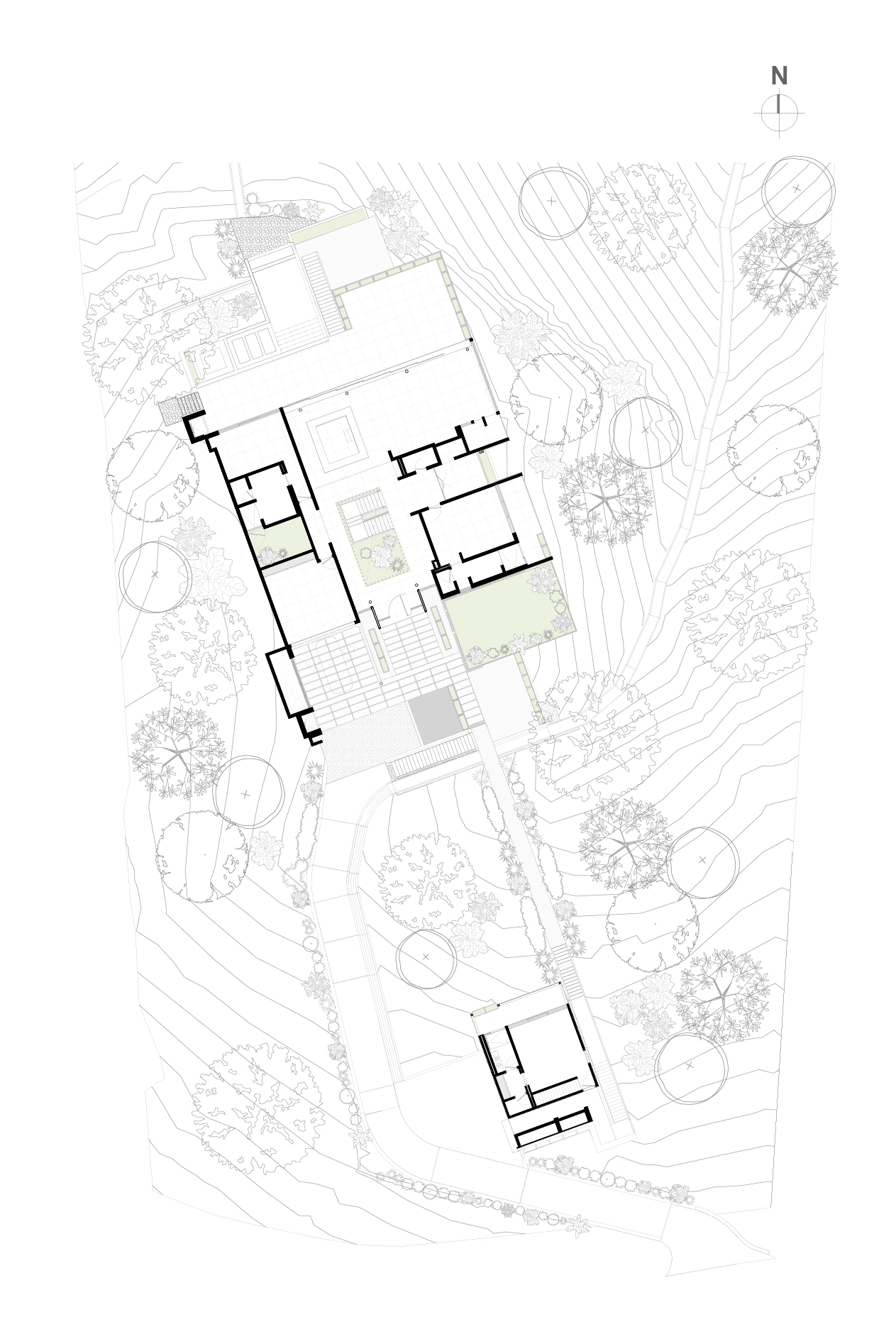 Site plan drawing showing a main building with courtyards, a smaller separate volume, and trees set among sloping contour lines