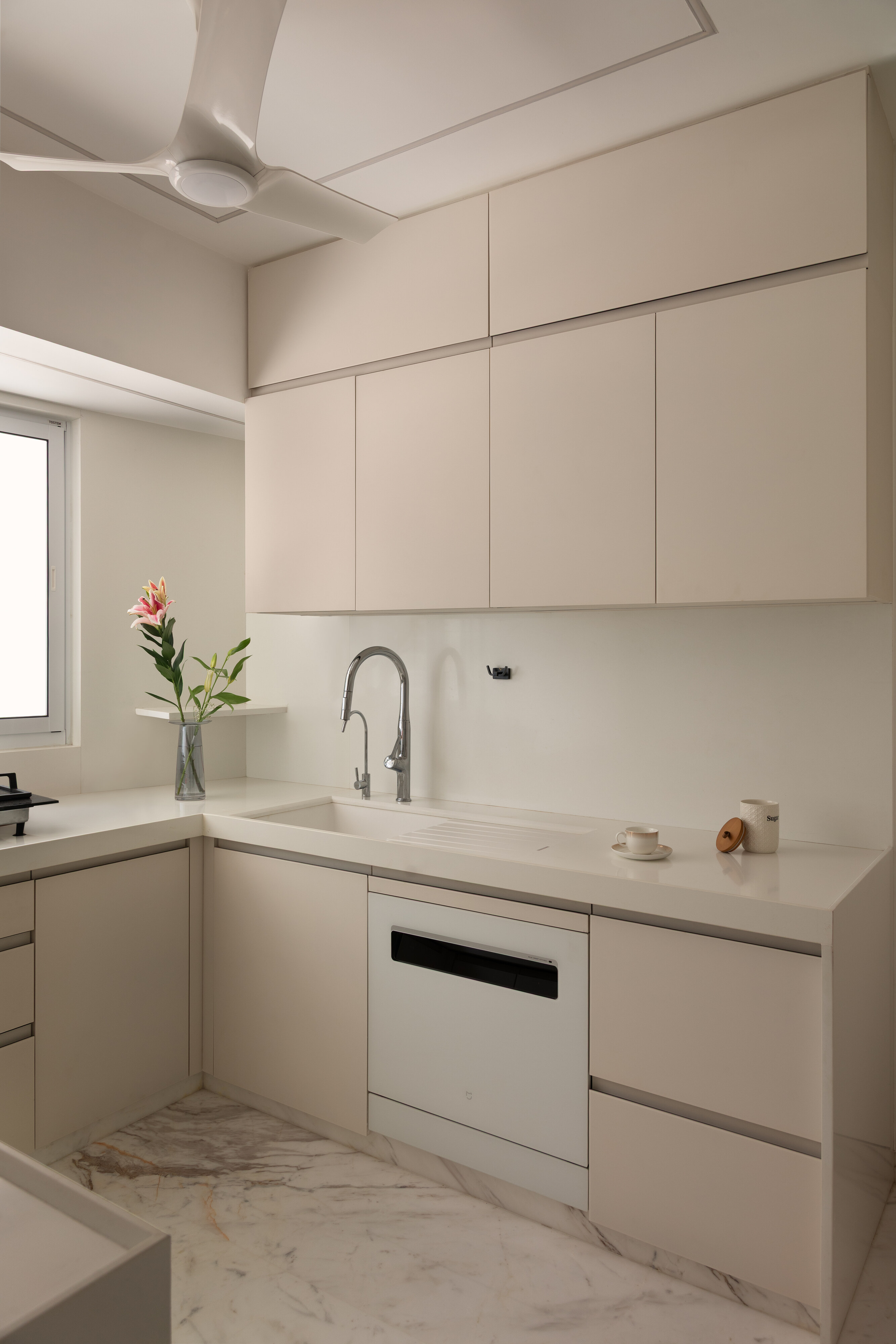 The L-shaped working kitchen continues the cream palette.