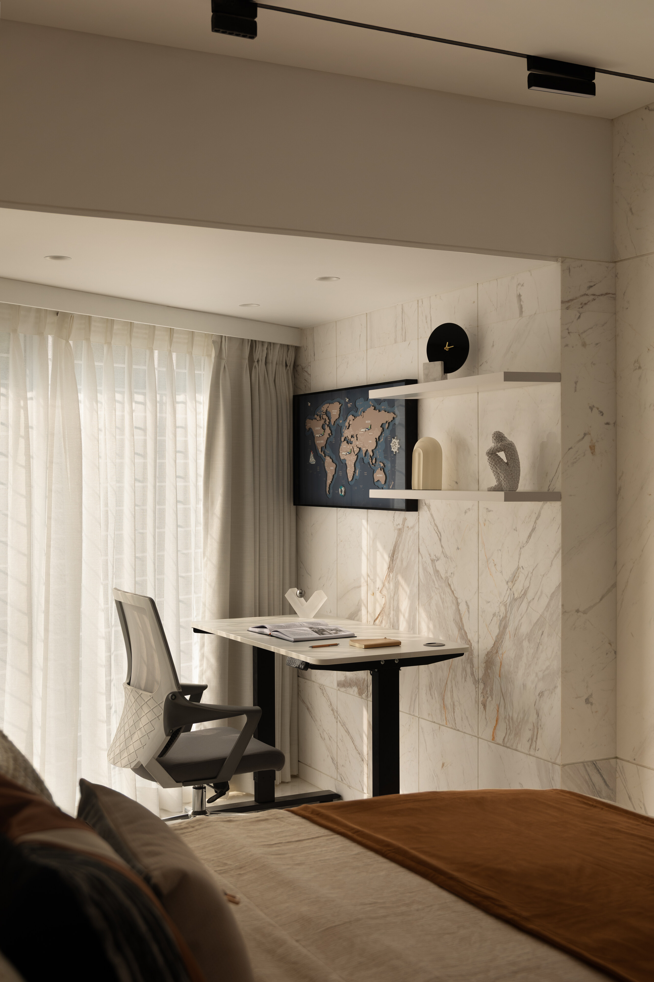 A study corner with a sit-stand desk and a marble feature wall.