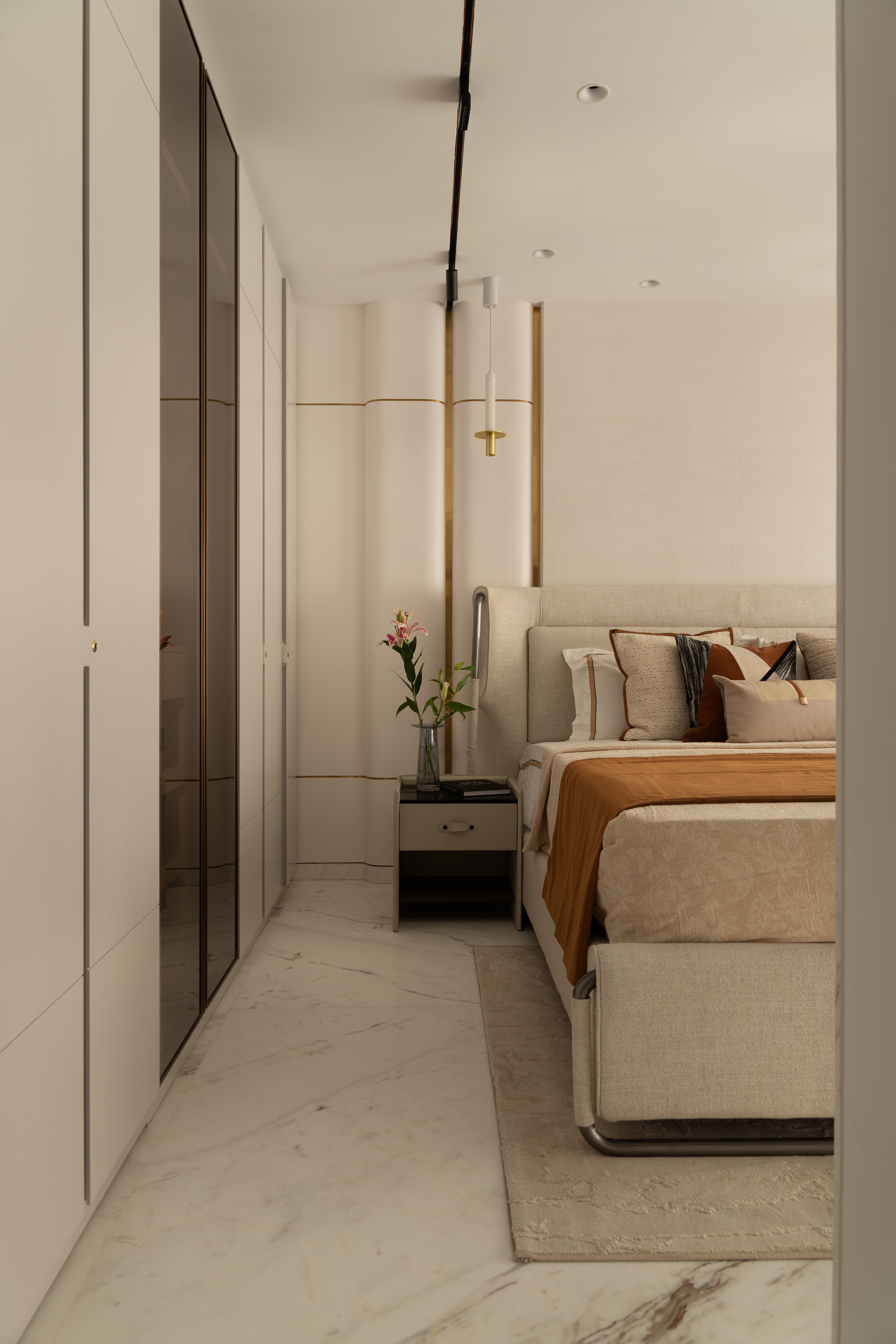 The dressing corridor: floor-to-ceiling mirrored wardrobes face a curved fluted feature wall in cream and brass.