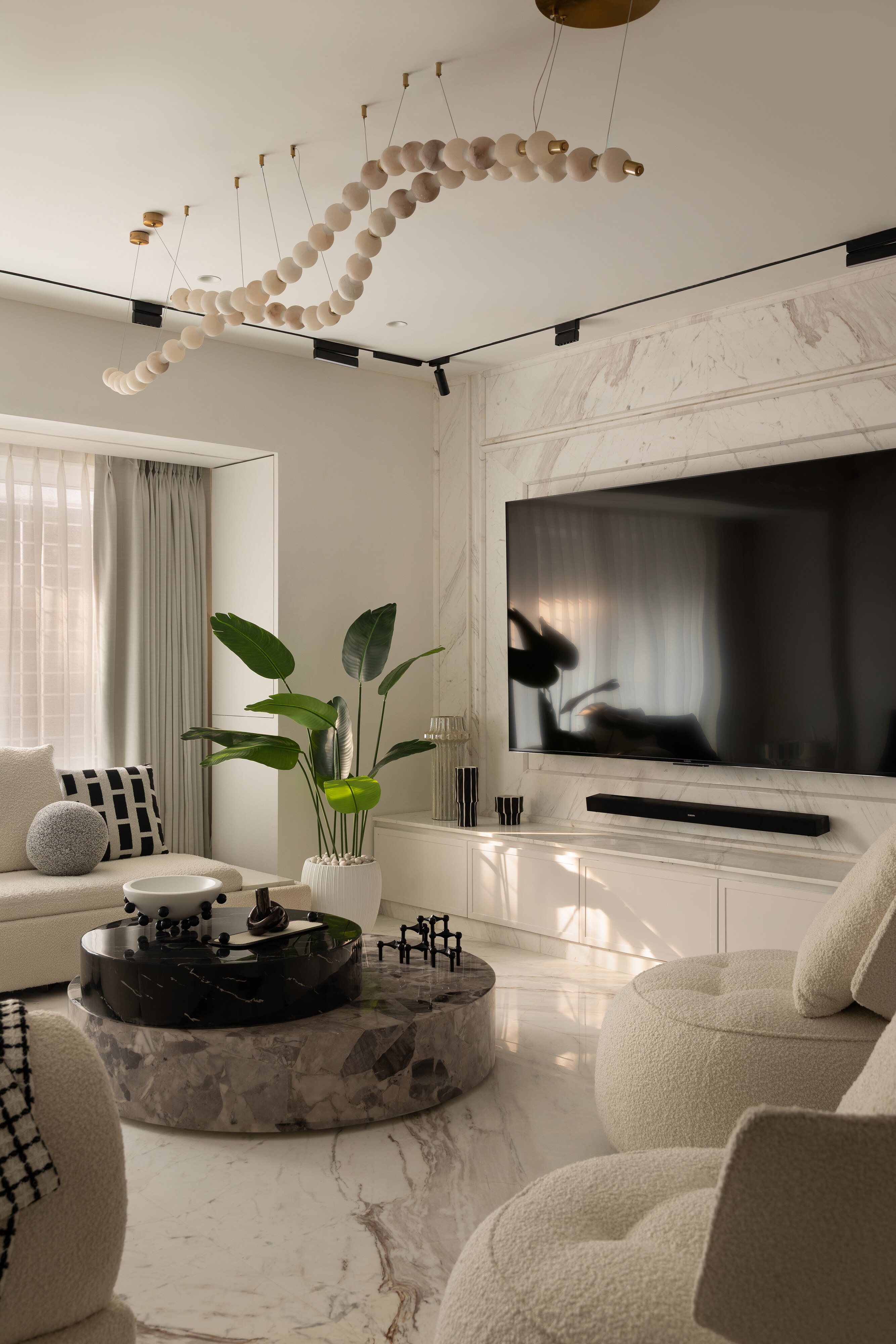 The living room, anchored by a marble-clad feature wall and a custom beaded ceiling installation.