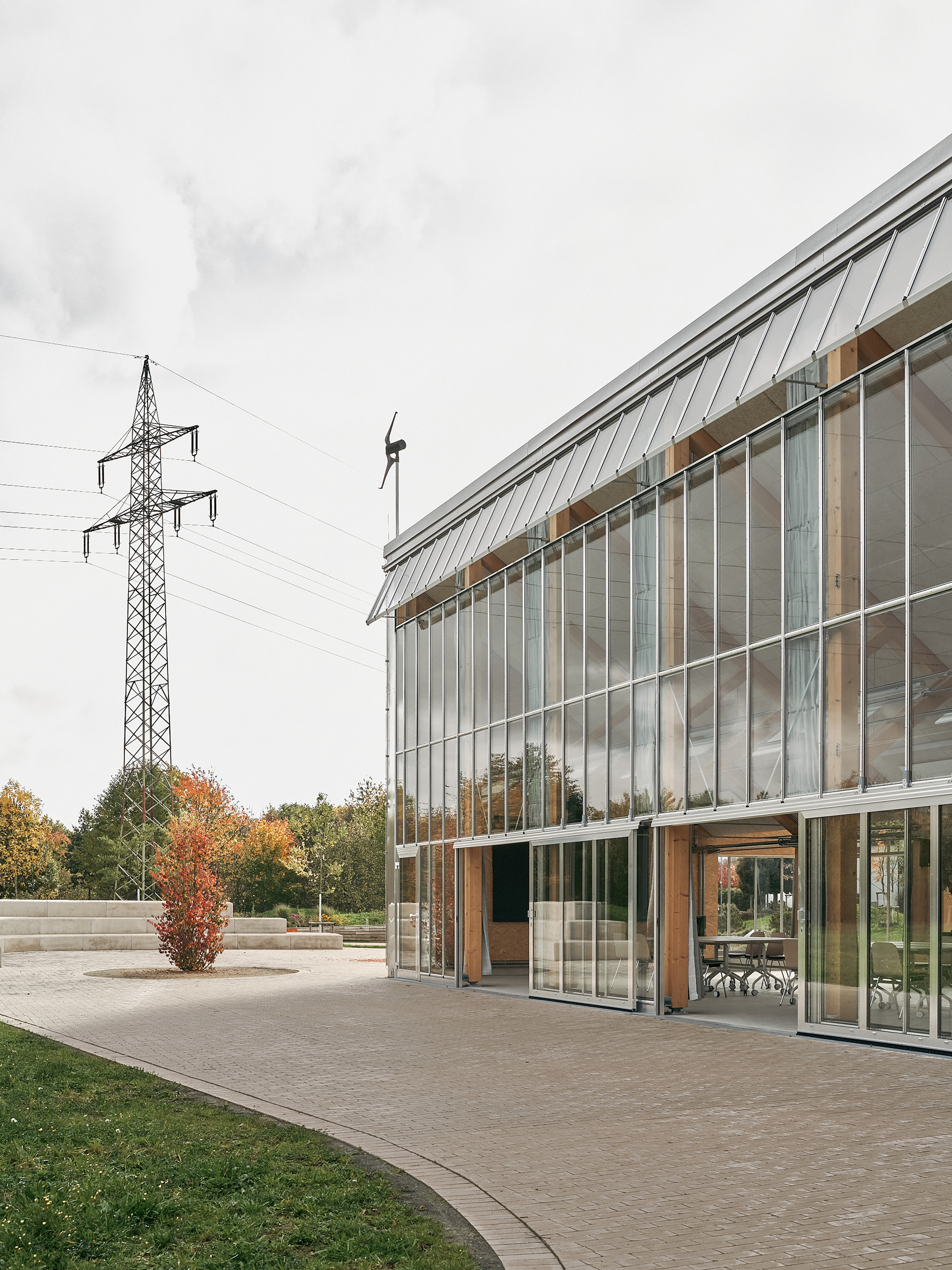 Greenhouse facade and corner entrance with a high-voltage pylon in the field beyond