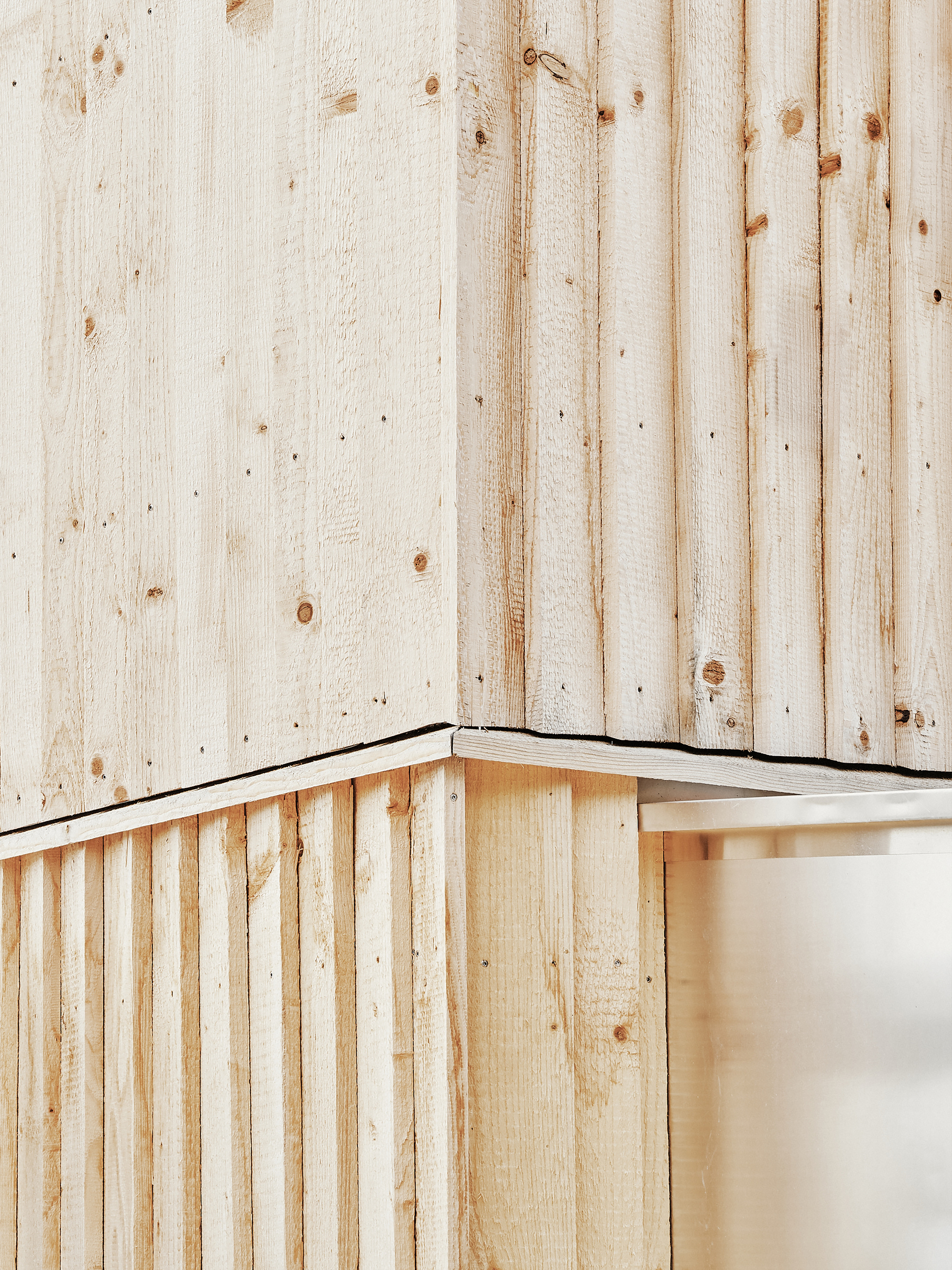 Close-up of an external corner showing two layers of vertical timber boarding