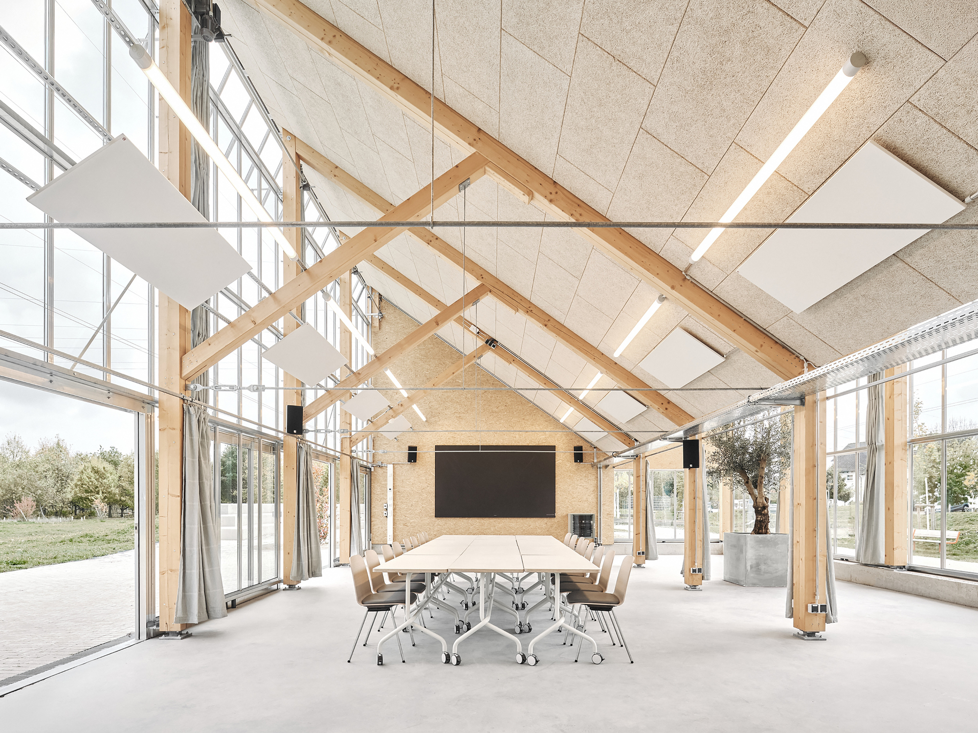 Central event space with a long table, screen and timber roof structure exposed