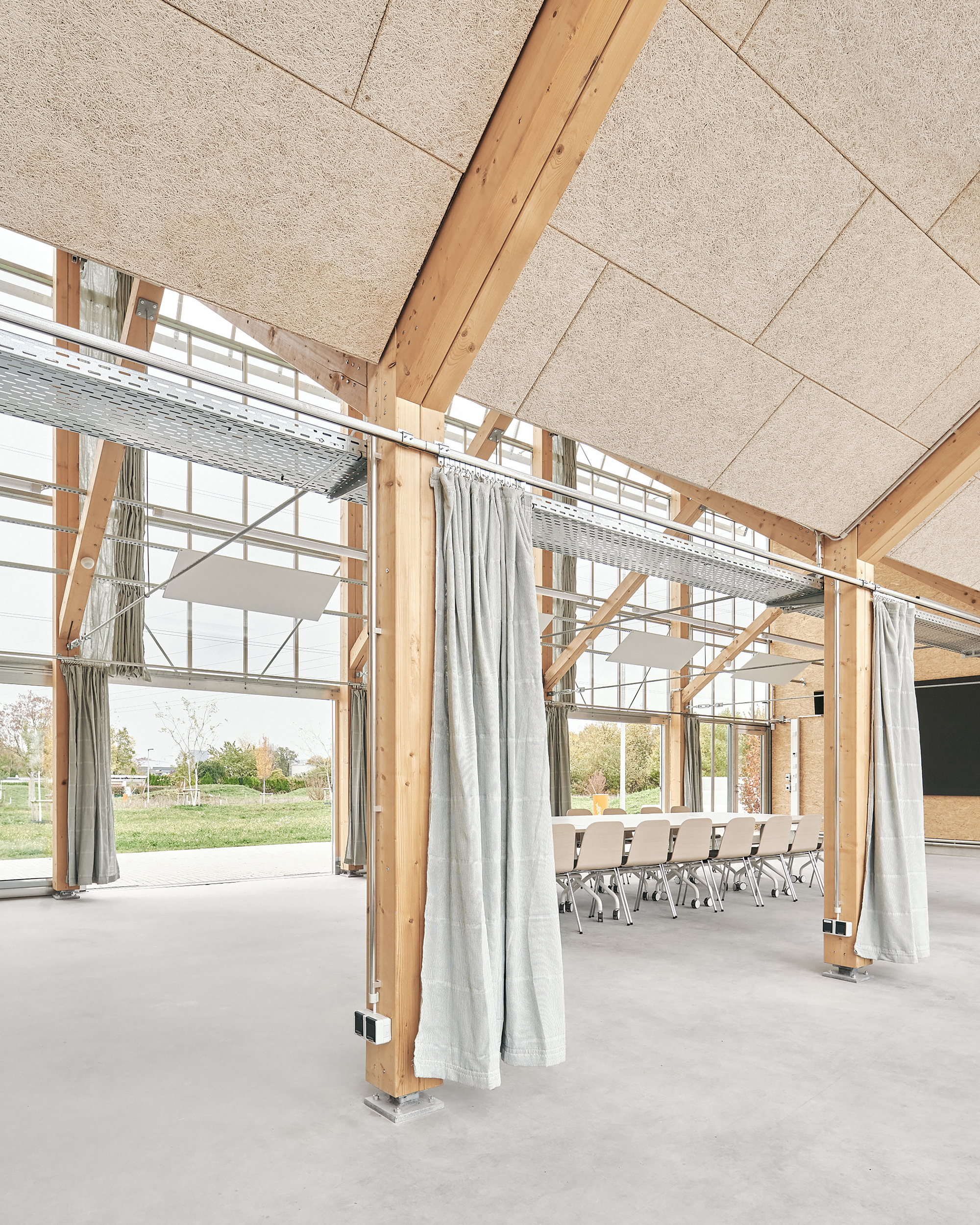 View along the greenhouse hall with linen curtains drawn between timber columns
