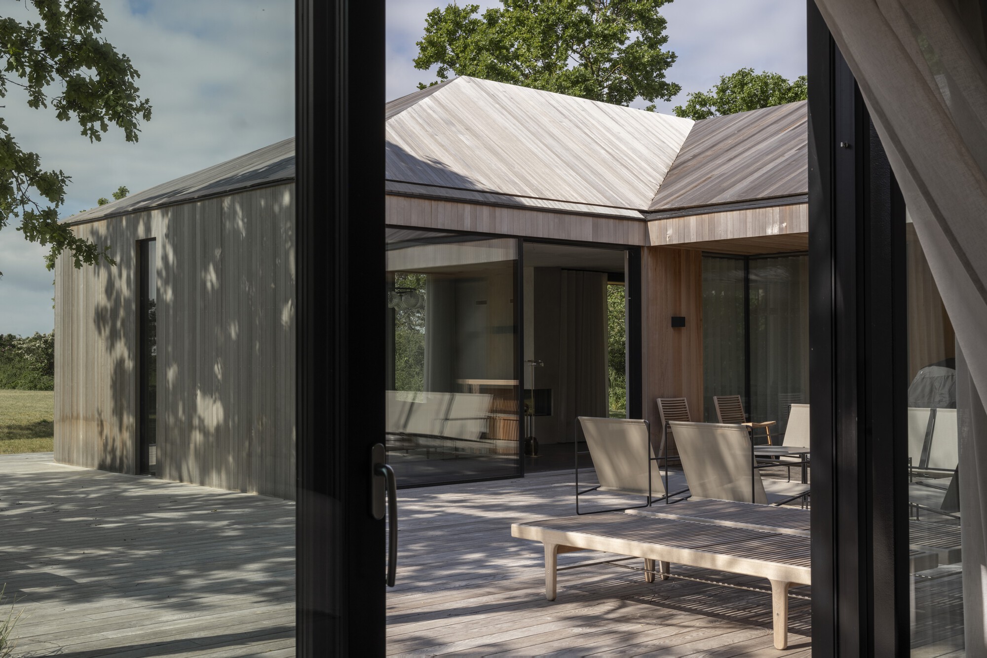 Timber courtyard with standing seam metal roofs visible through glazed corner opening