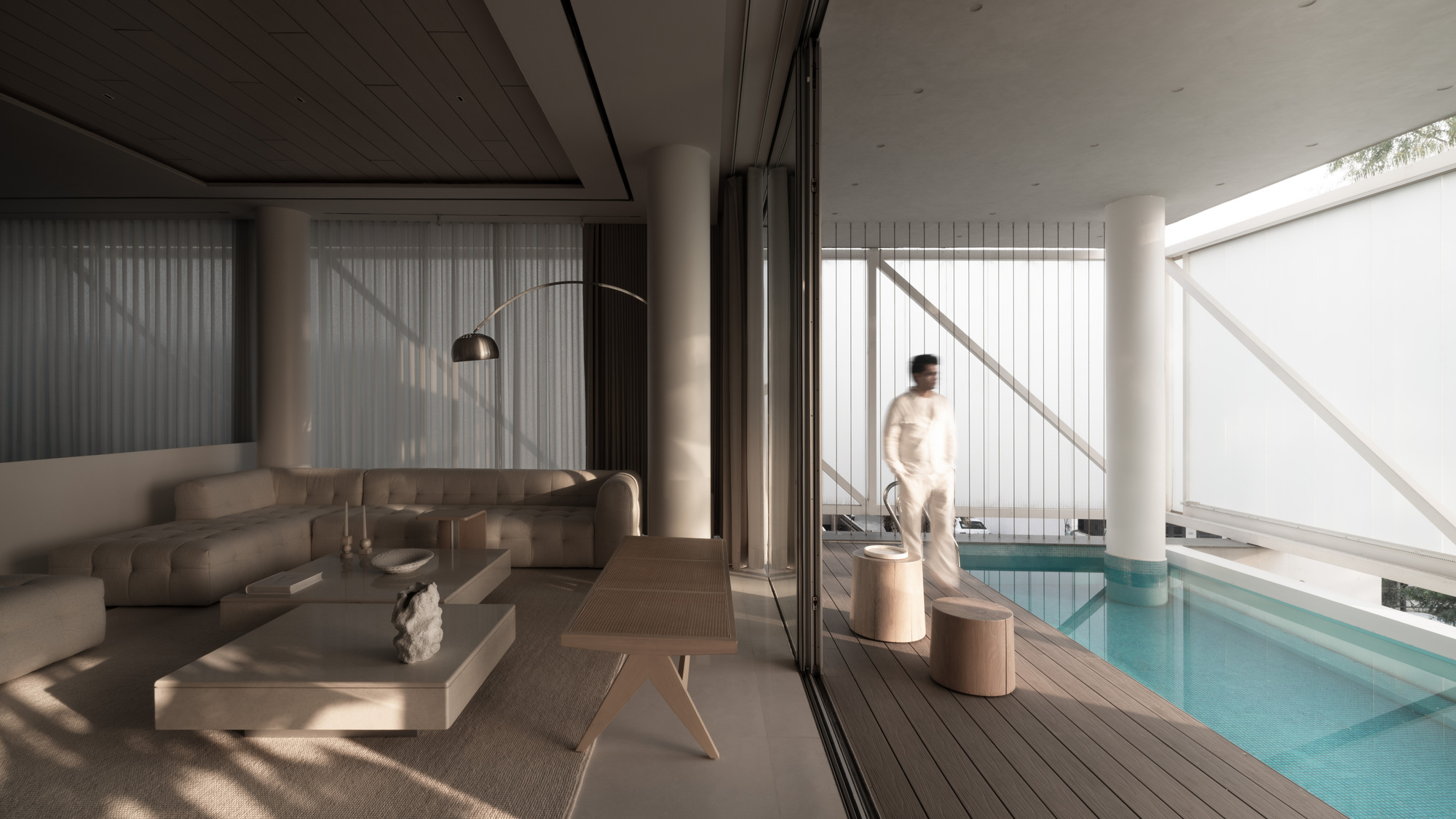 Living area opening onto timber pool deck with a person standing near folded sliding glass doors