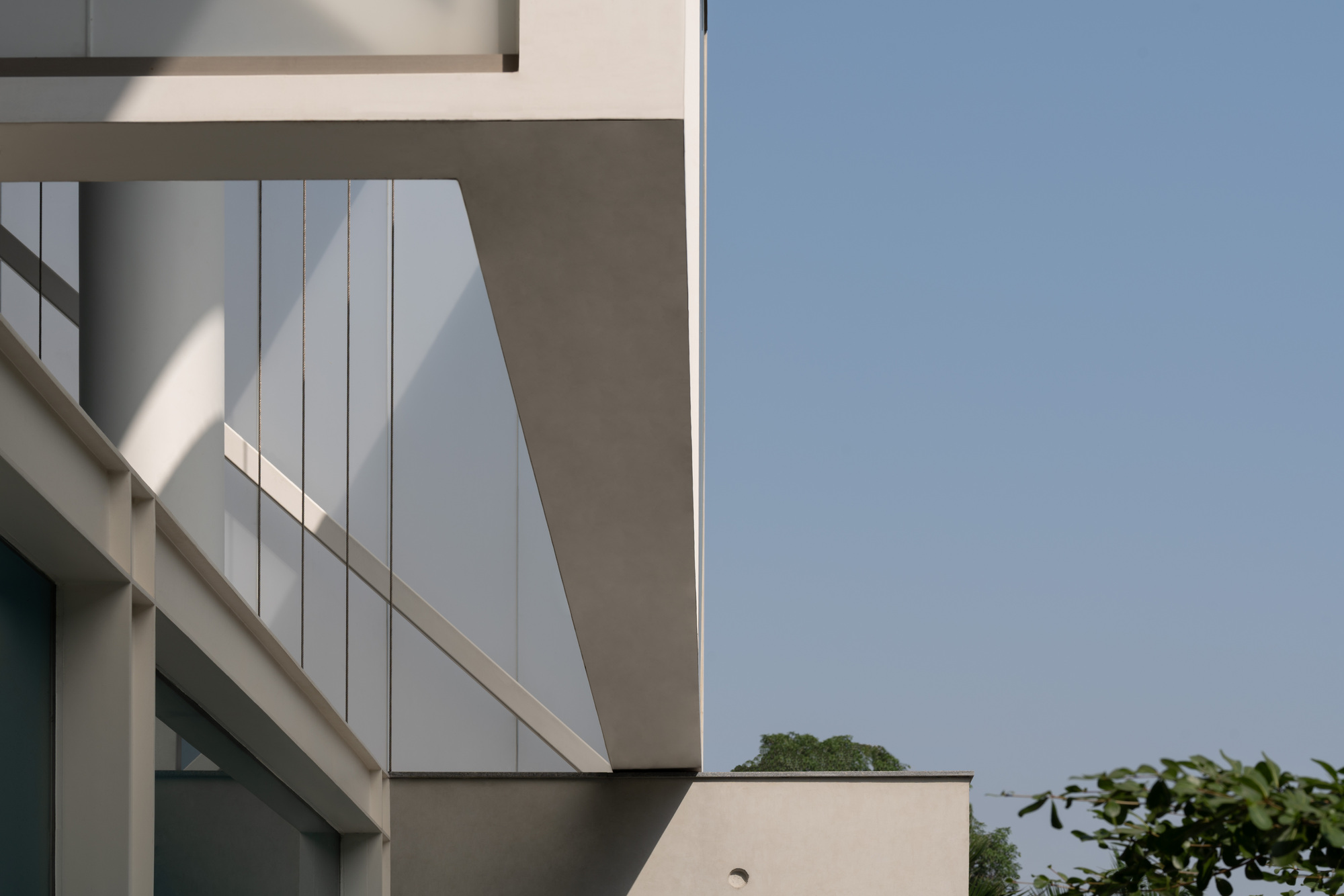 Projecting volume clad in white vertical panels cantilevering over the lower floor against a clear sky