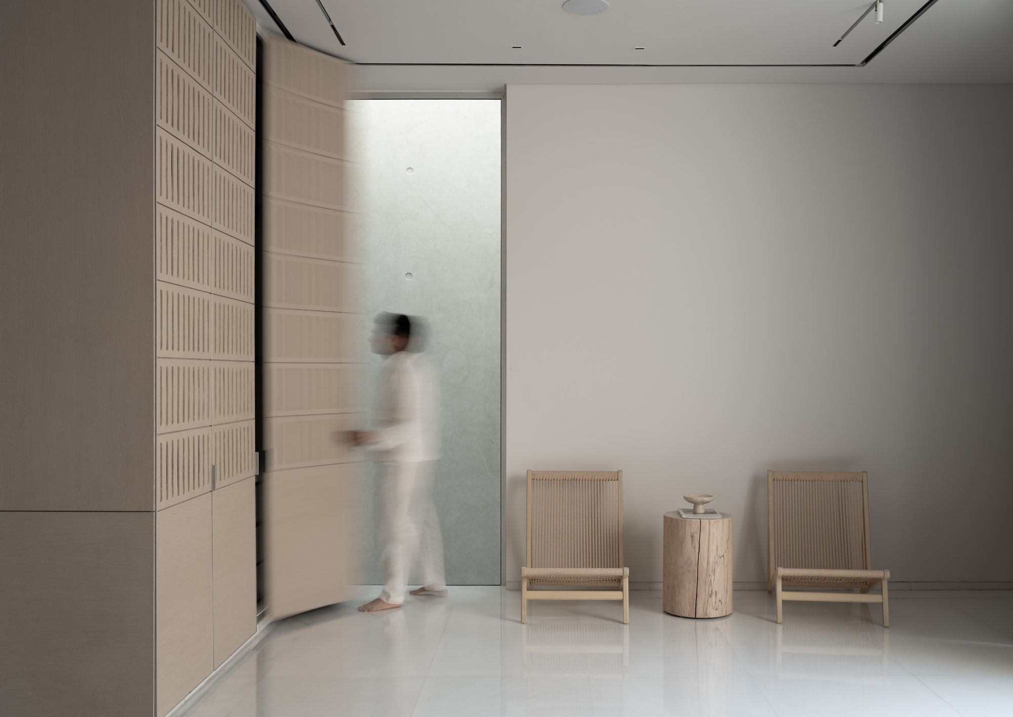 Entryway with fluted wall paneling and a blurred figure passing through the doorway