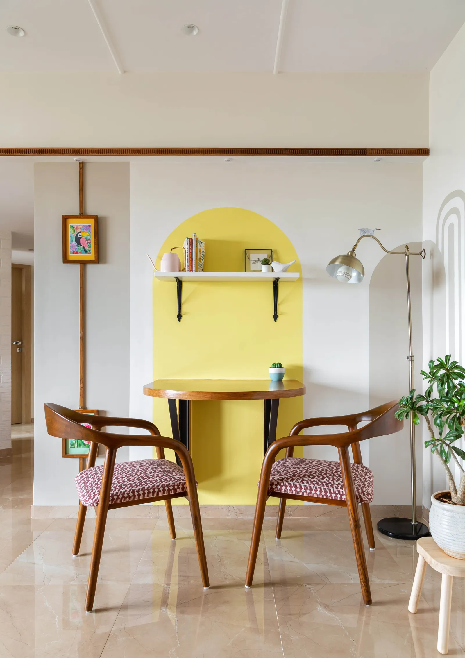 A drop-down wooden dining table for two is anchored visually to a yellow half-obround yellow form. The chairs are by Kridva Design. Anuja Kambli