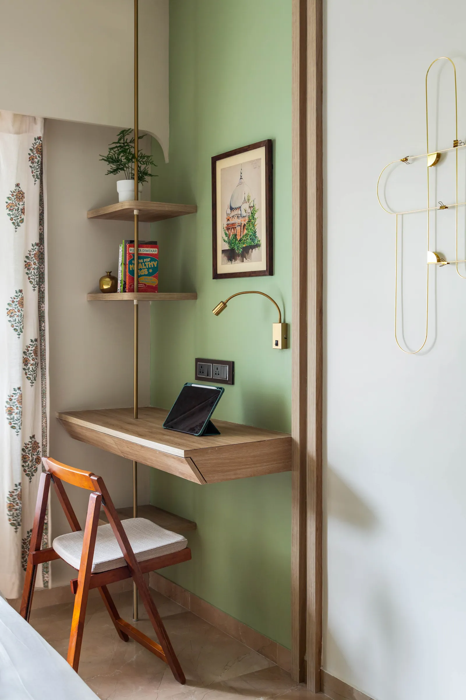 The study unit in the primary bedroom has shelves attached to a long brass rod. The metallic detail finds continuity in the wardrobe handles, knobs and wall hangings. Anuja Kambli