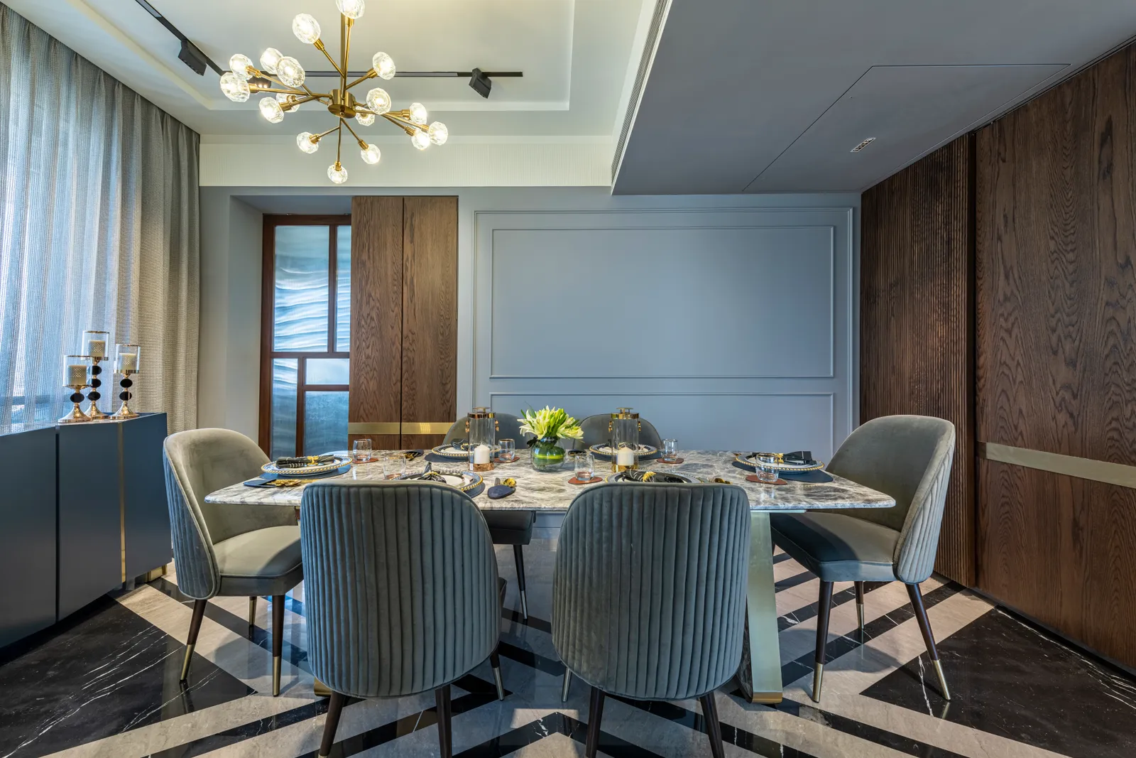 In the dining room, an elongated stone table takes centre stage, while ribbed chairs add a tactile touch. A gilded chandelier gives the room a glam spin. PRASHANT BHAT