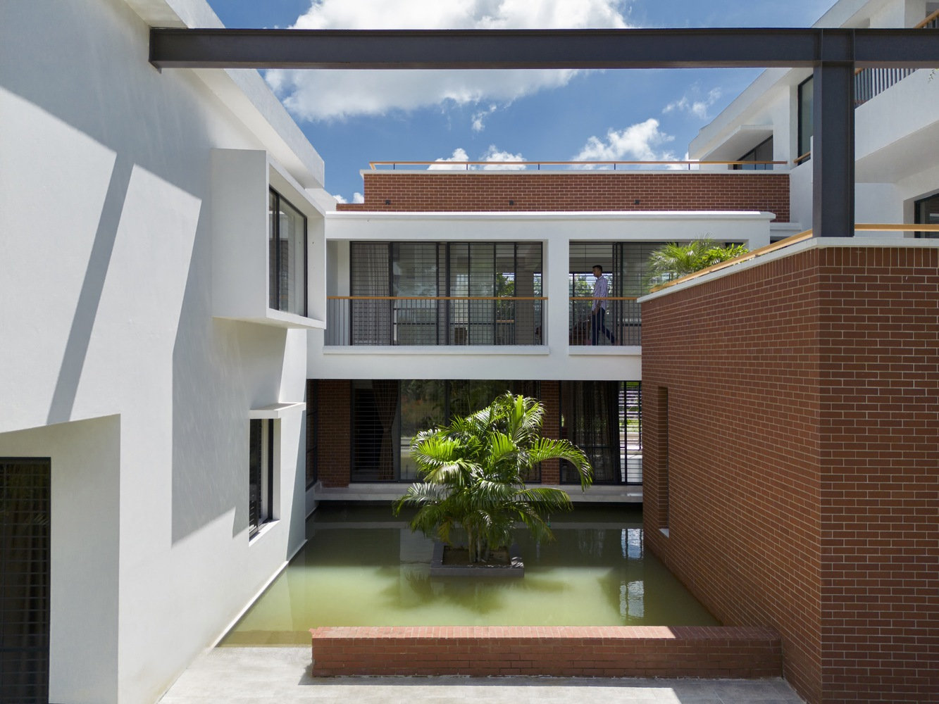 Interior courtyard pool surrounded by white plaster and red brick walls under a sunny sky