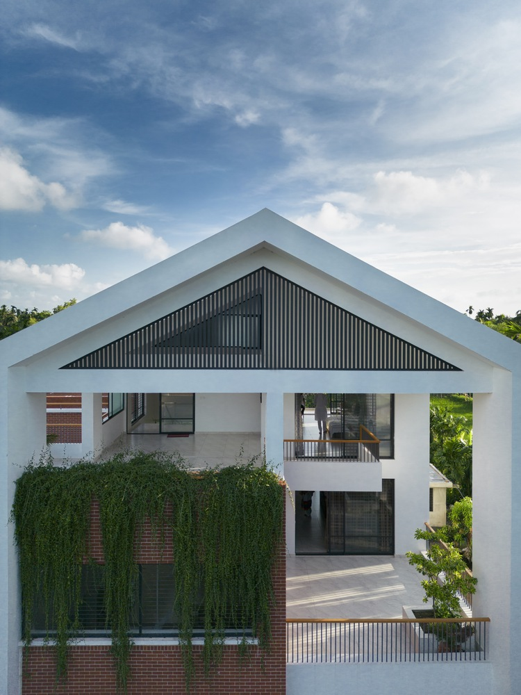 White gable frame enclosing a dark corrugated panel with brick and green climbing vines below
